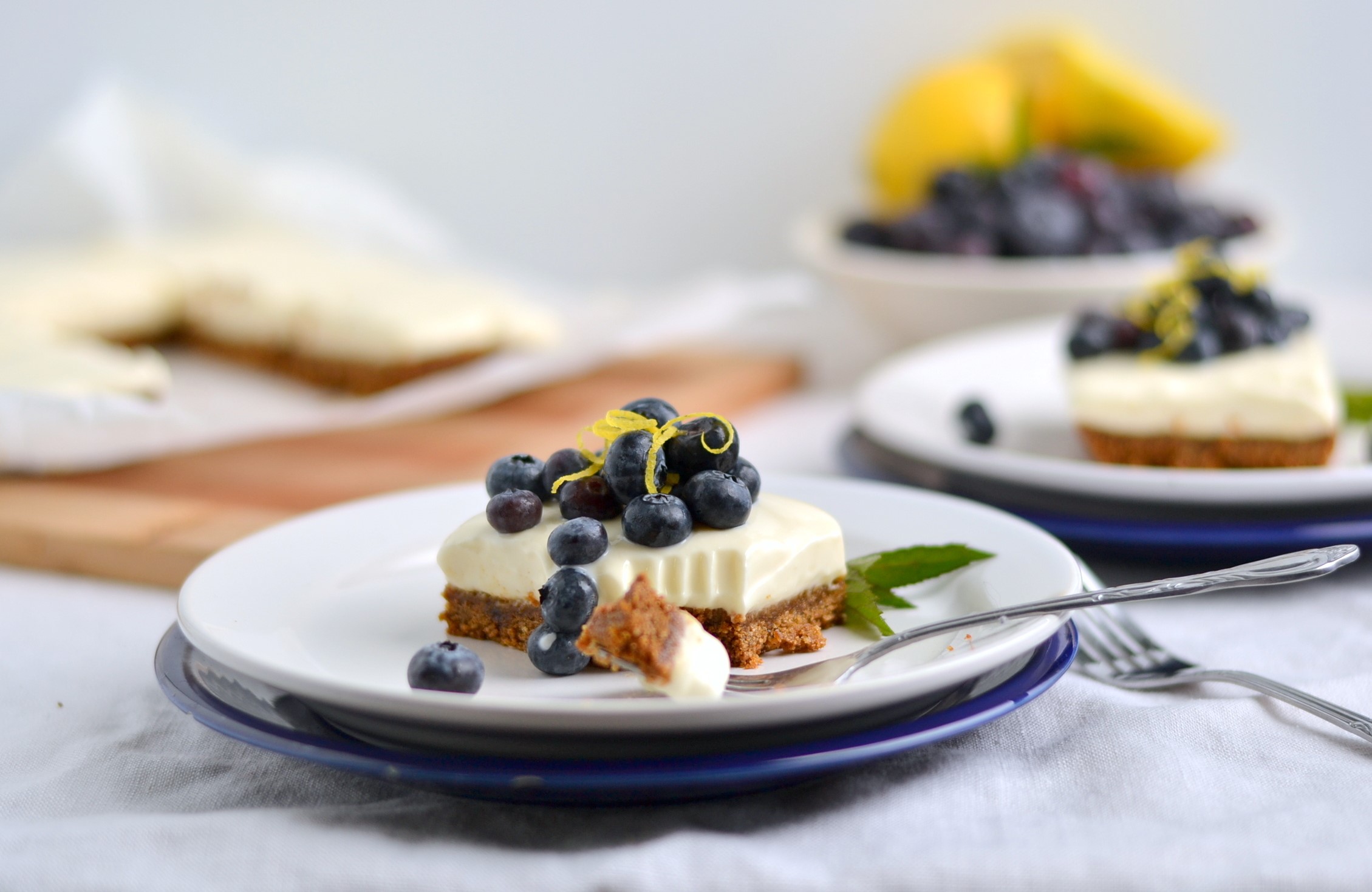 Blueberry cheesecake slices on plates with lemons and blueberries HD Wallpaper