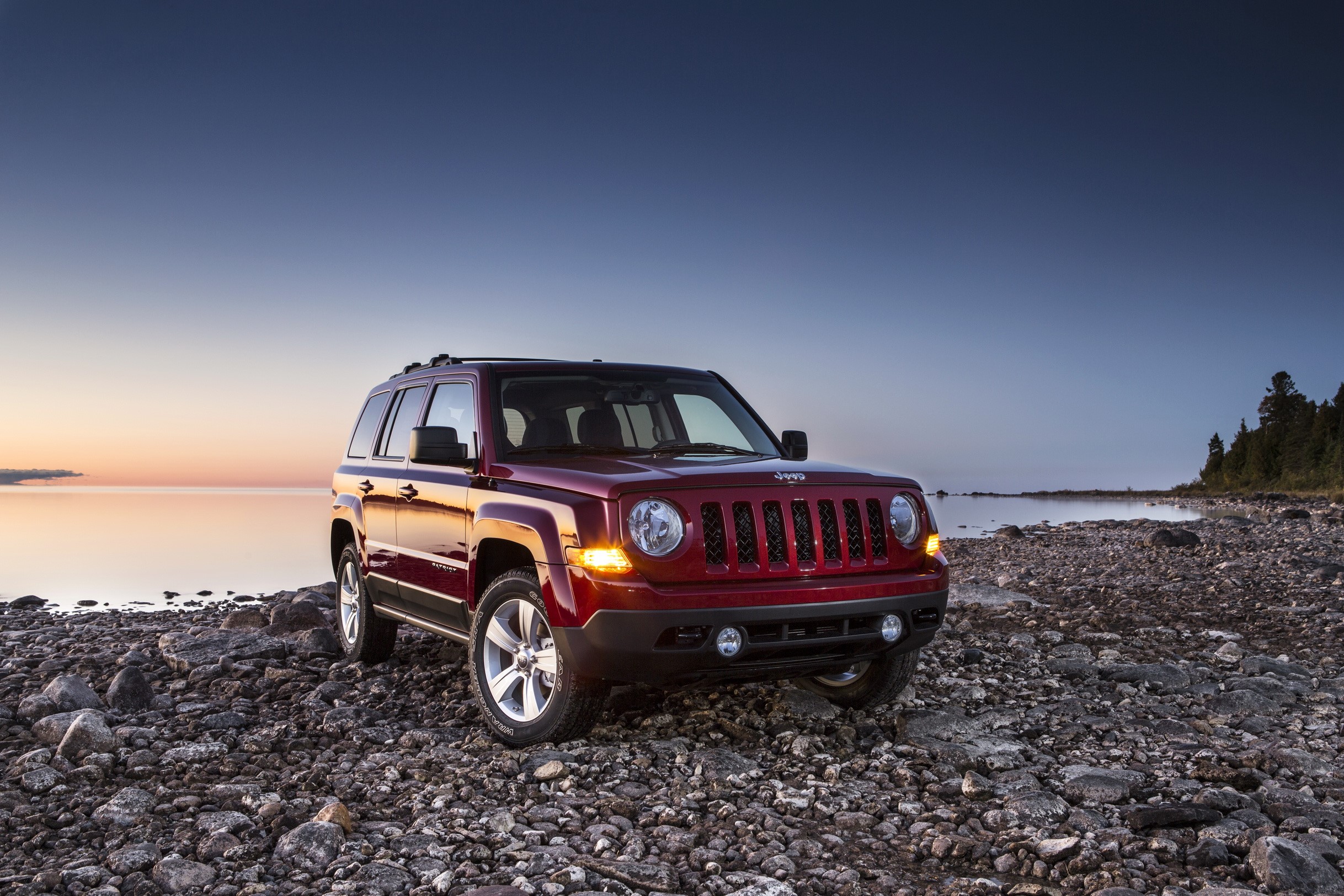 Red Jeep Patriot on a rocky shore at sunset HD Wallpaper