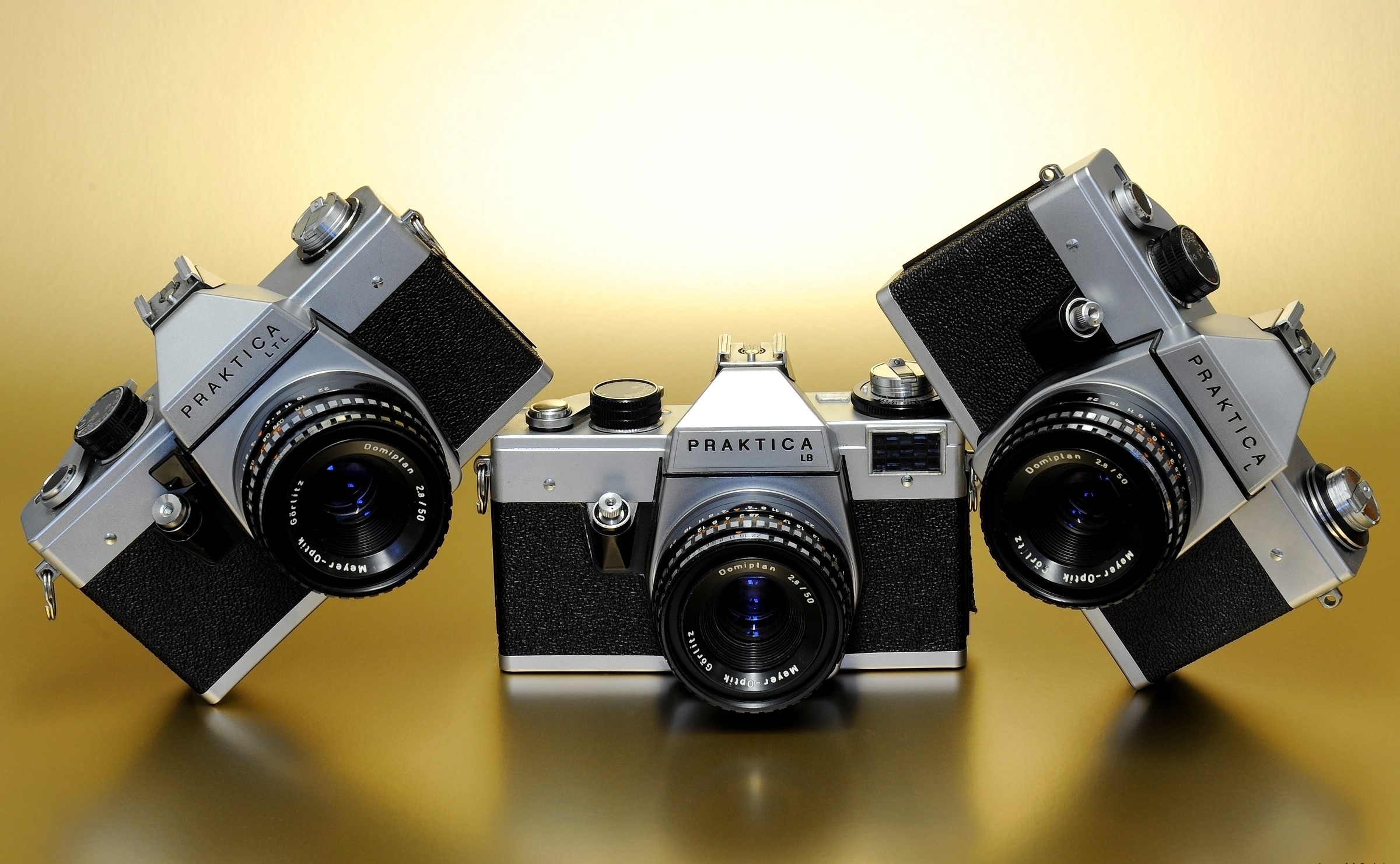 Three Praktica LTL LB L cameras on a gold surface HD Wallpaper
