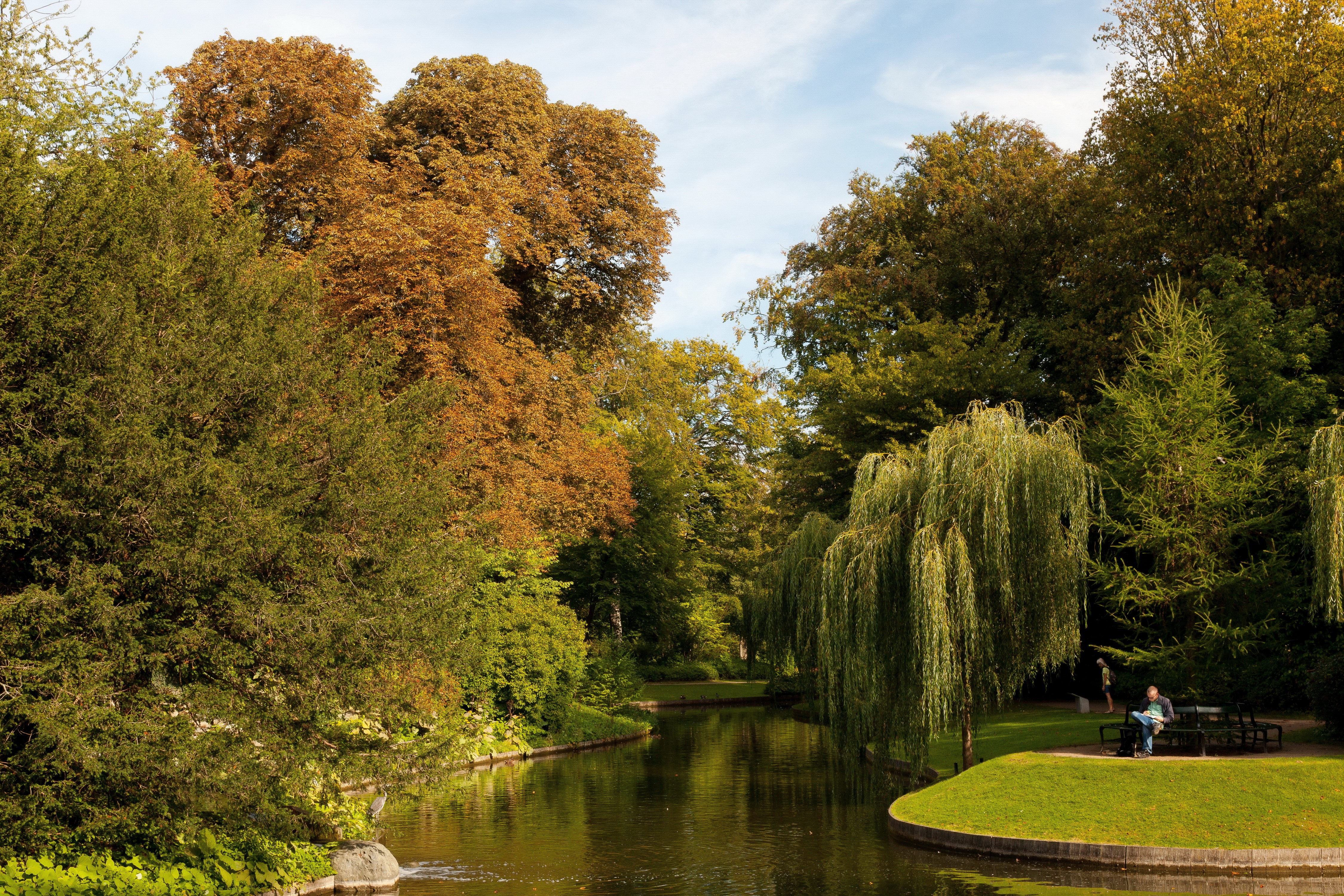 Canal in a park with autumn trees and people on a bench HD Wallpaper