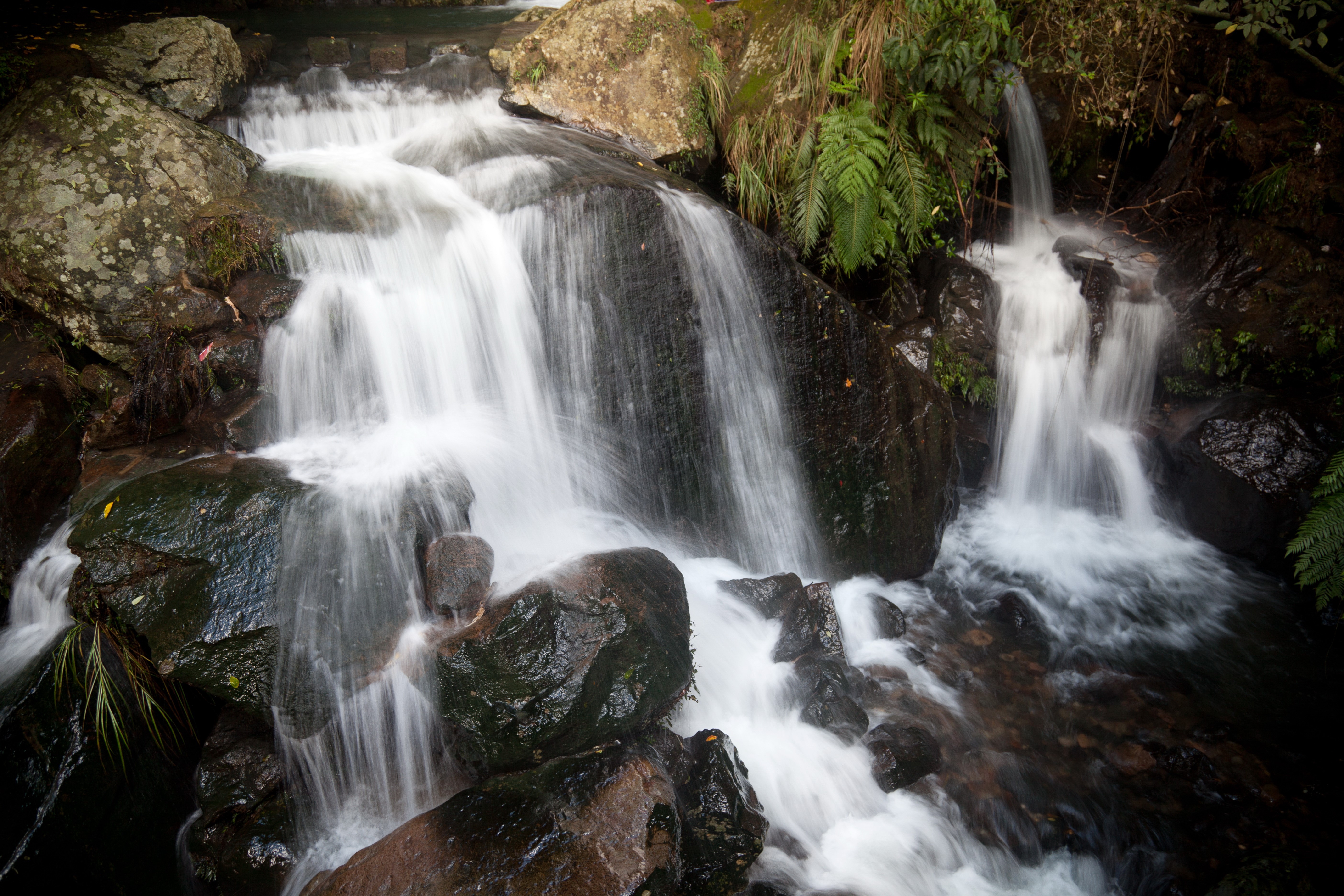 Waterfalls cascading over dark stones HD Wallpaper