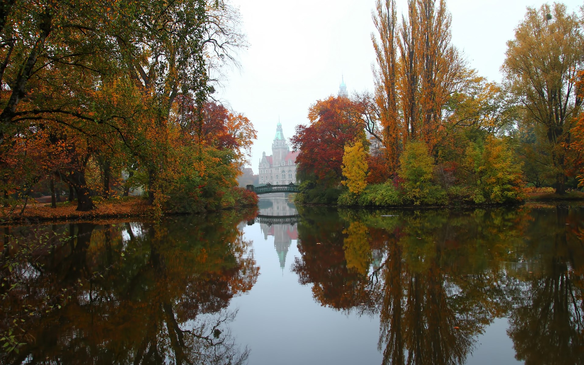 Autumn trees reflected in a lake with a castle in the background HD Wallpaper