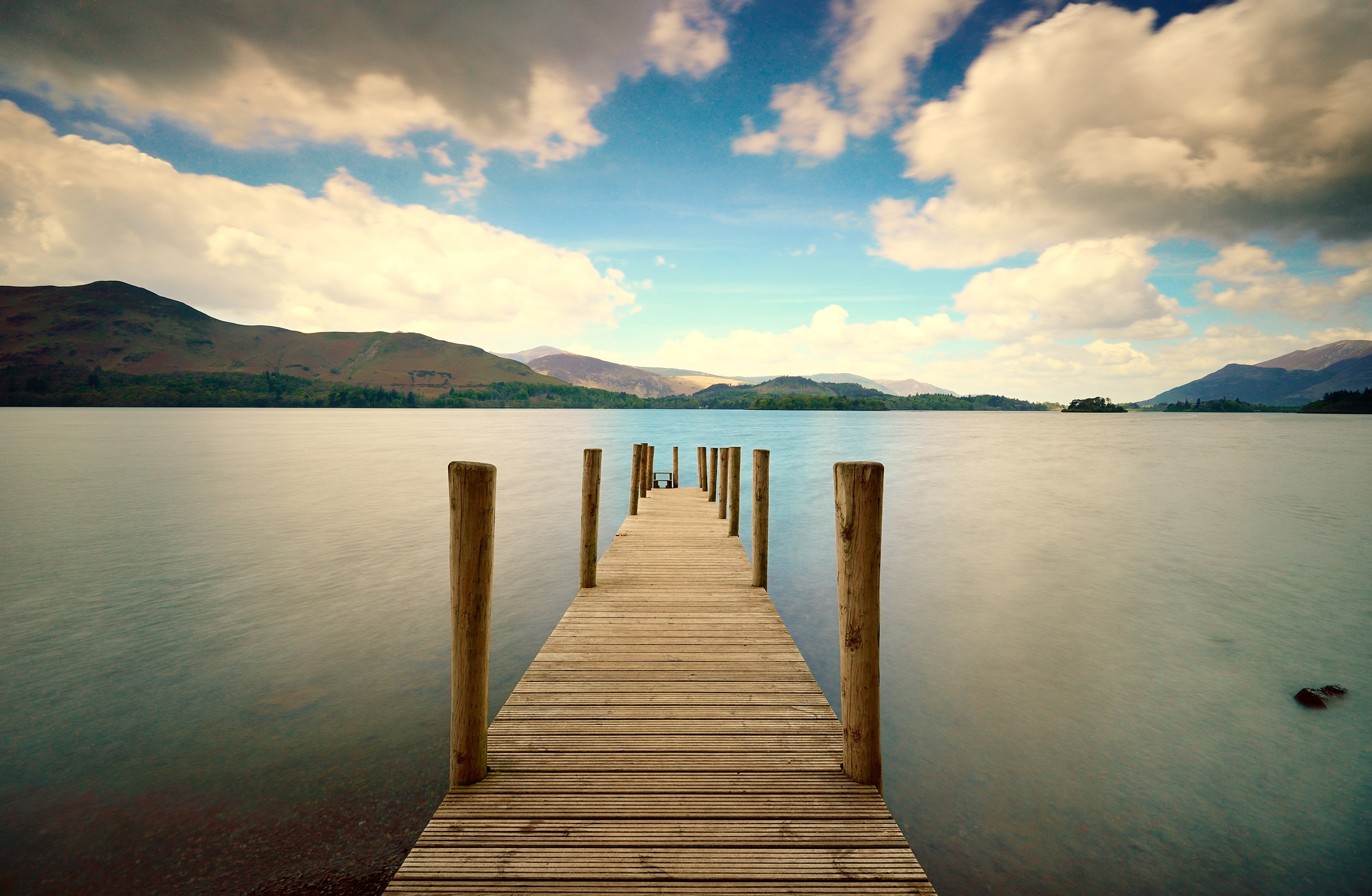 Wooden pier on a lake with mountains and clouds HD Wallpaper