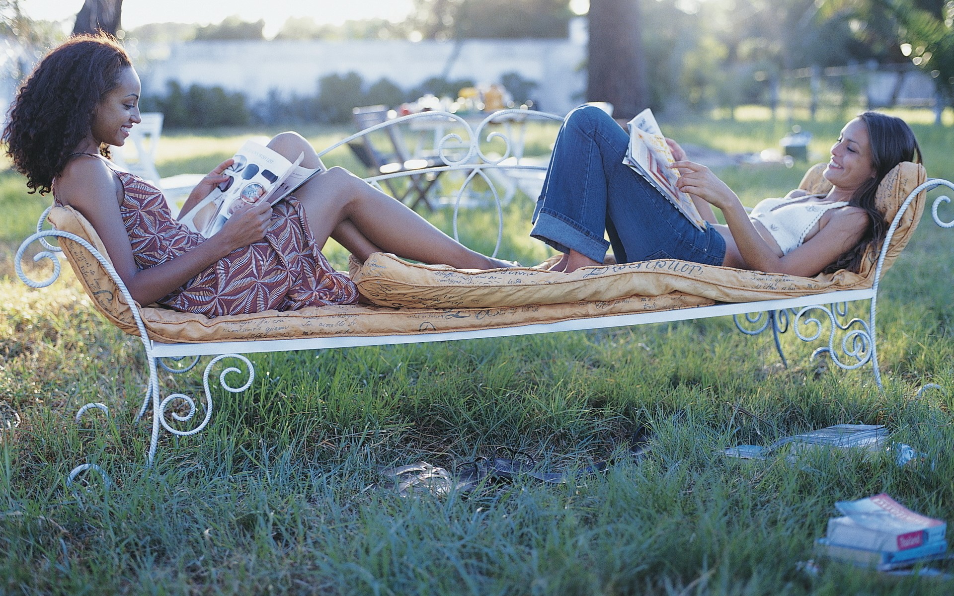 Two women relaxing on a chaise lounge outdoors HD Wallpaper