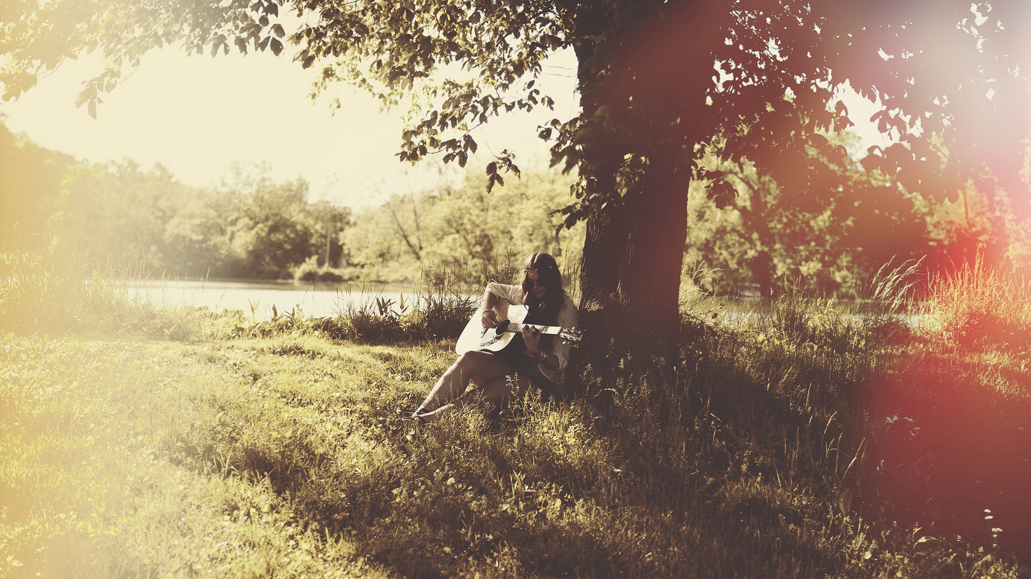 Woman playing guitar under a tree by a lake HD Wallpaper