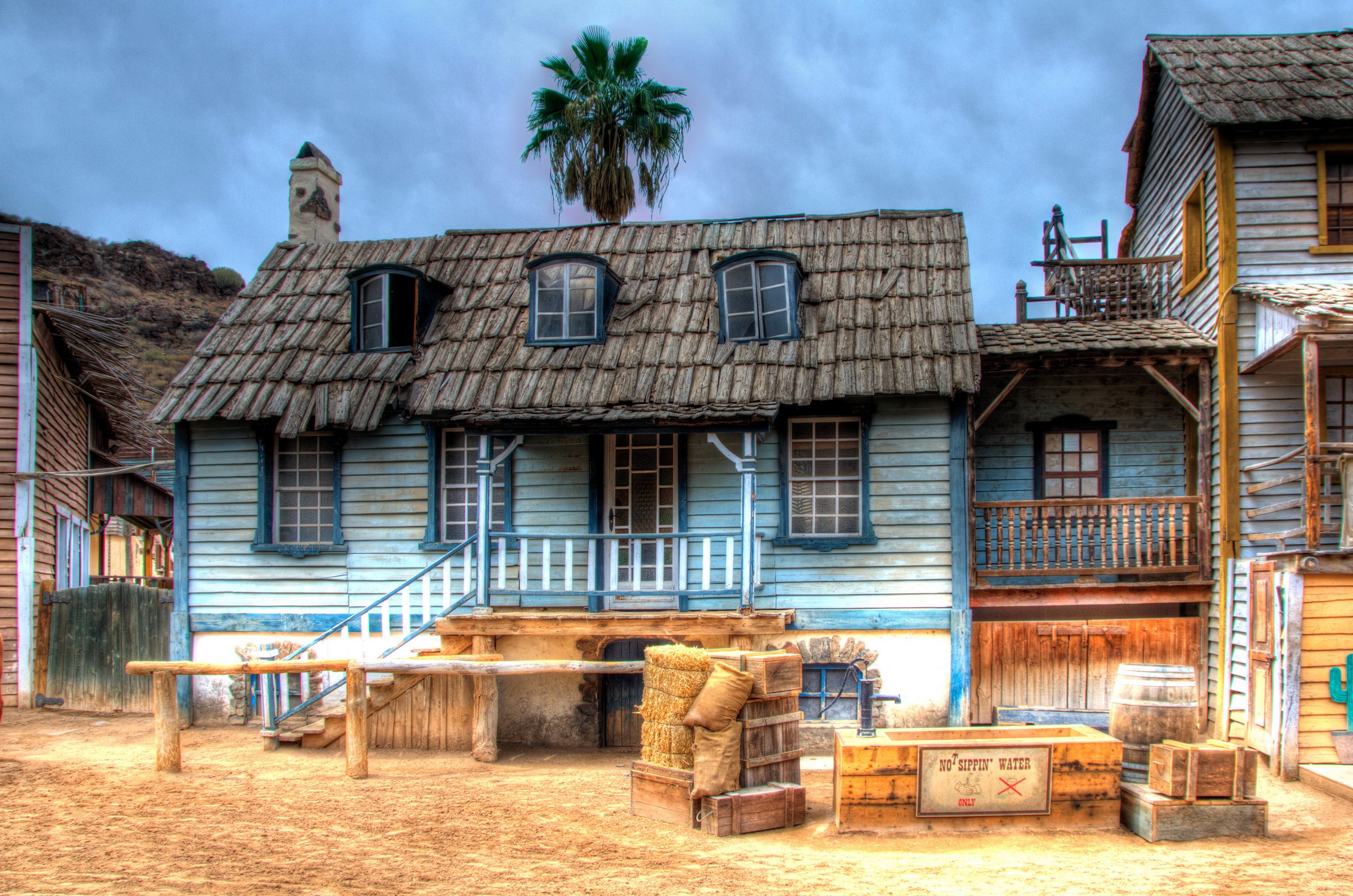 Western town with wooden buildings and a palm tree HD Wallpaper