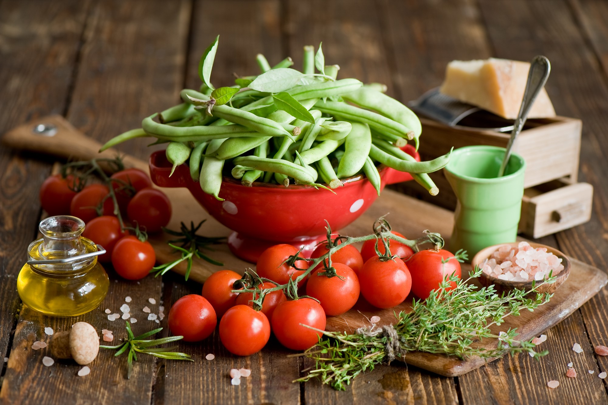 Green beans, tomatoes, olive oil, herbs, and cheese on a wooden table HD Wallpaper
