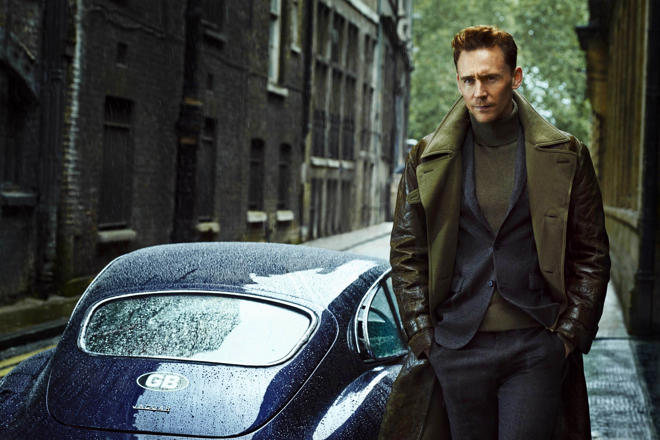 Tom Hiddleston in a suit next to a Jaguar HD Wallpaper