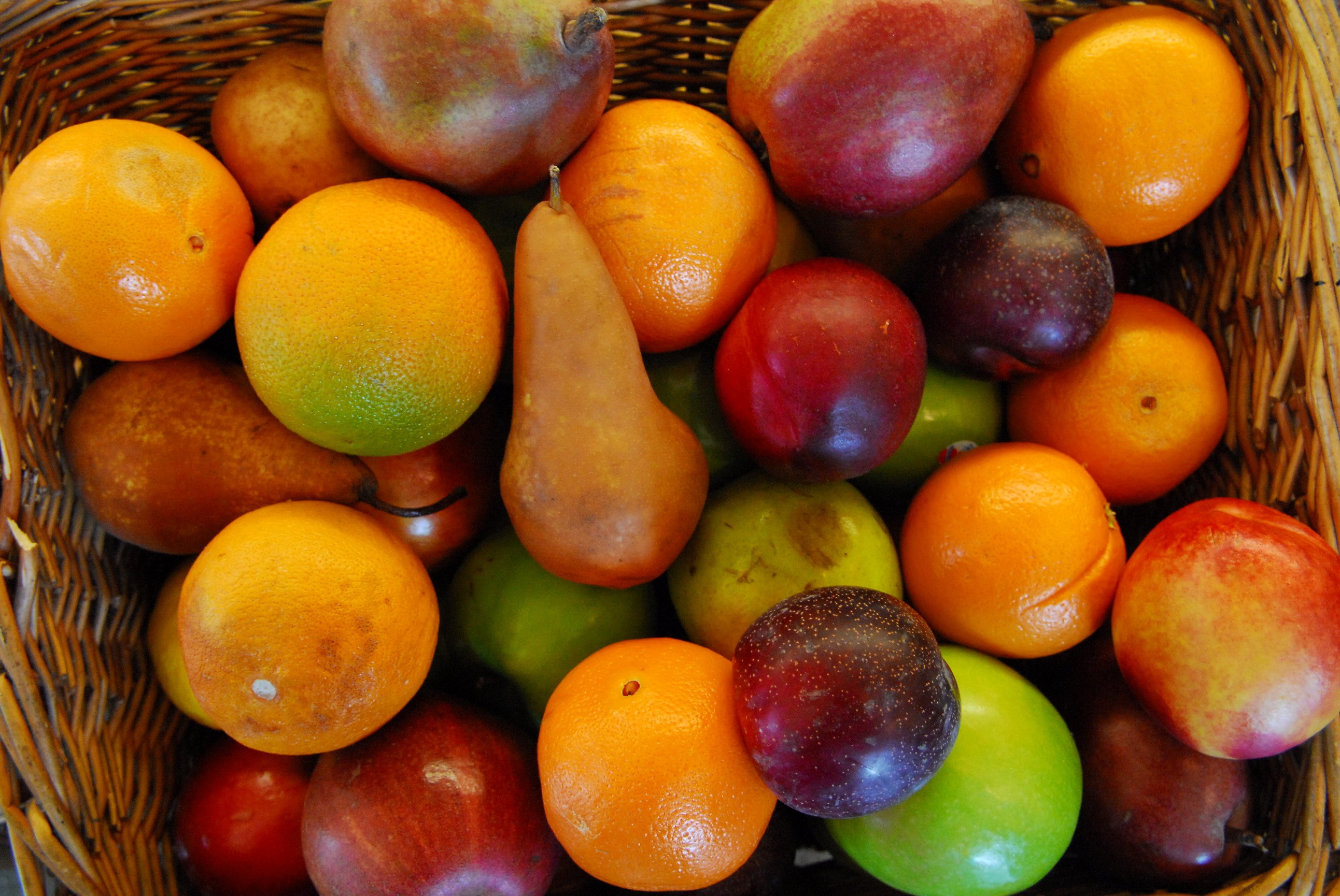 Basket of assorted fruits including oranges, pears, and plums HD Wallpaper