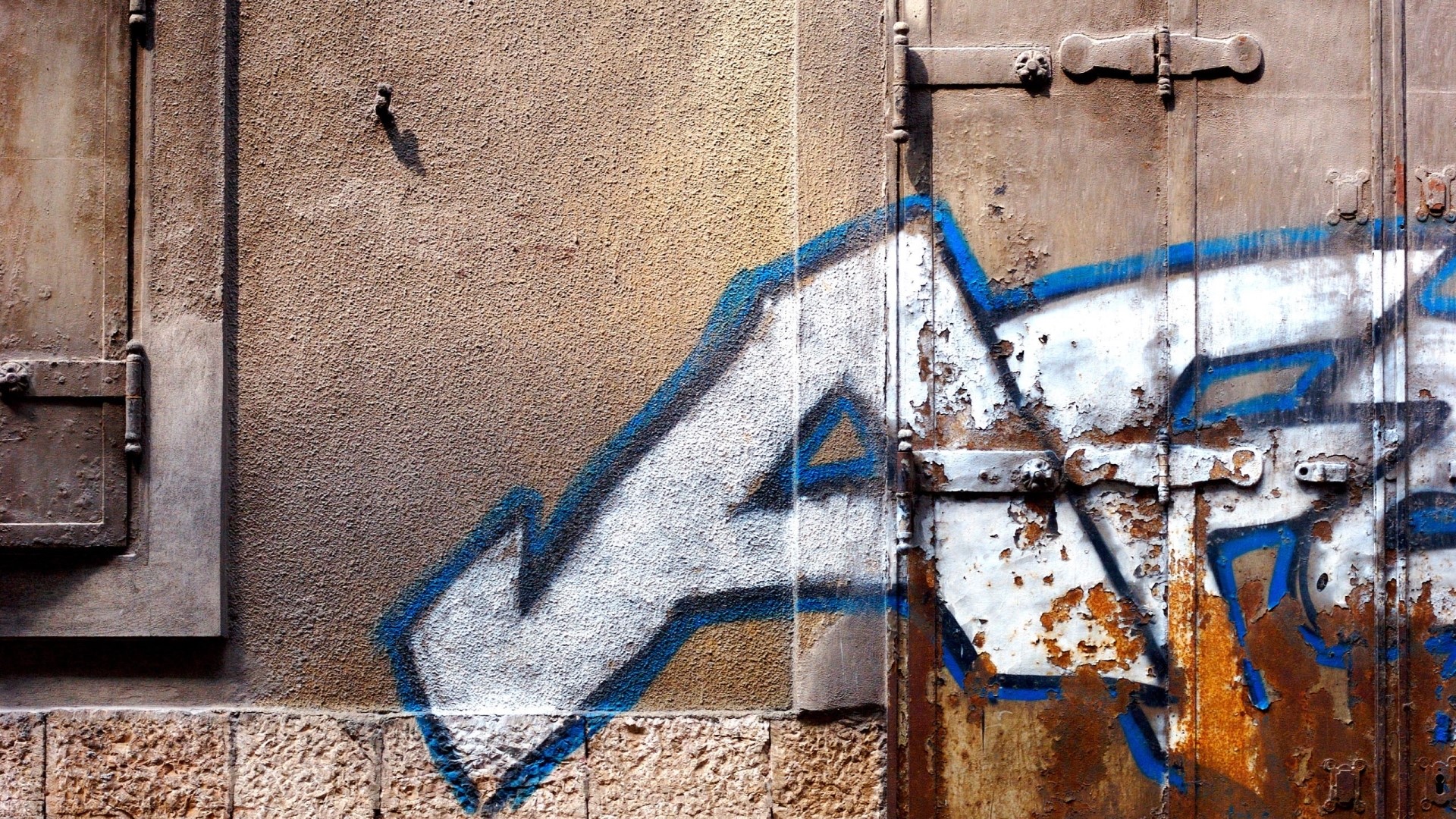 Graffiti on a textured wall and rusty metal door HD Wallpaper