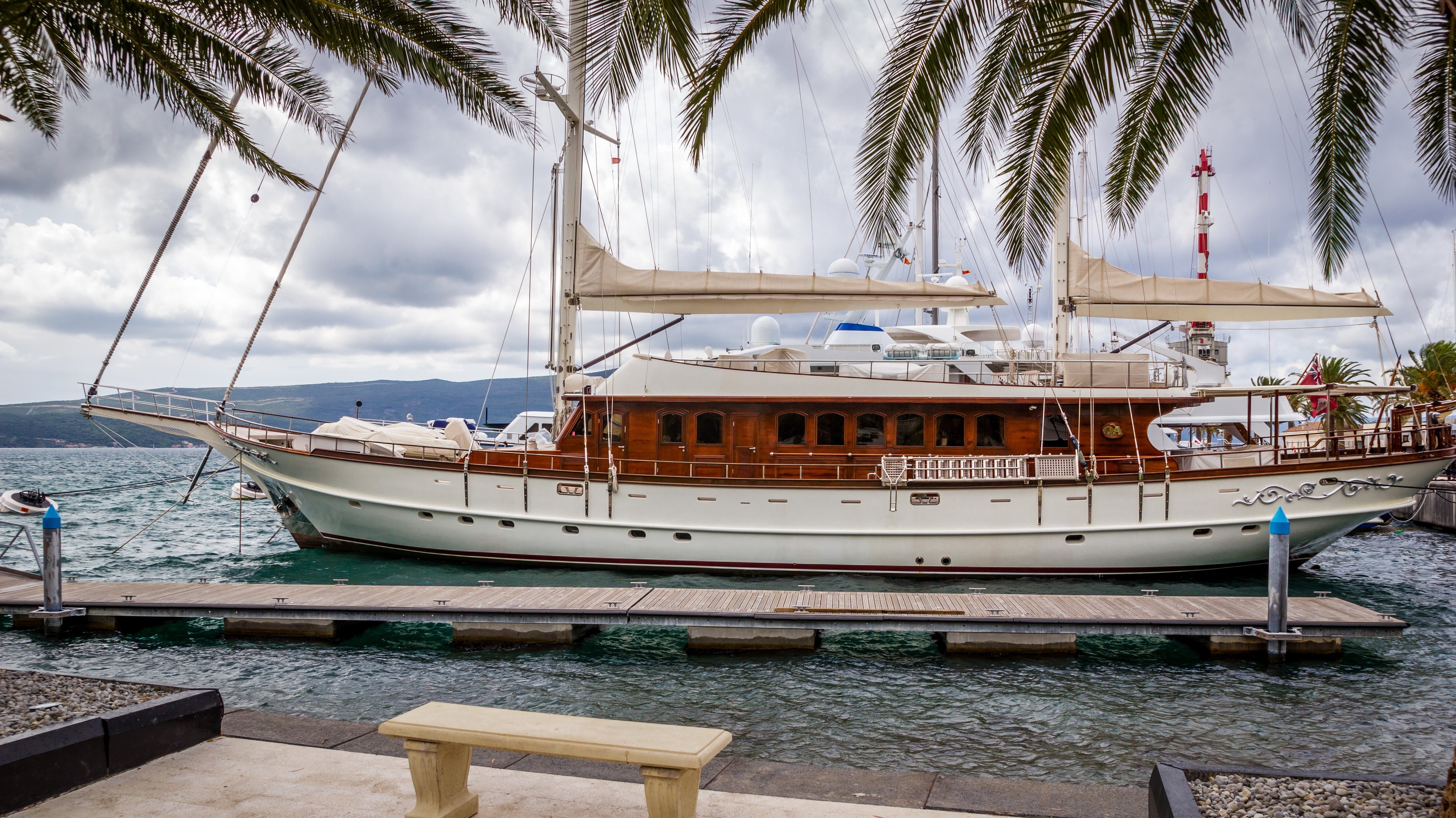 Sailing yacht docked at a marina with palm trees HD Wallpaper