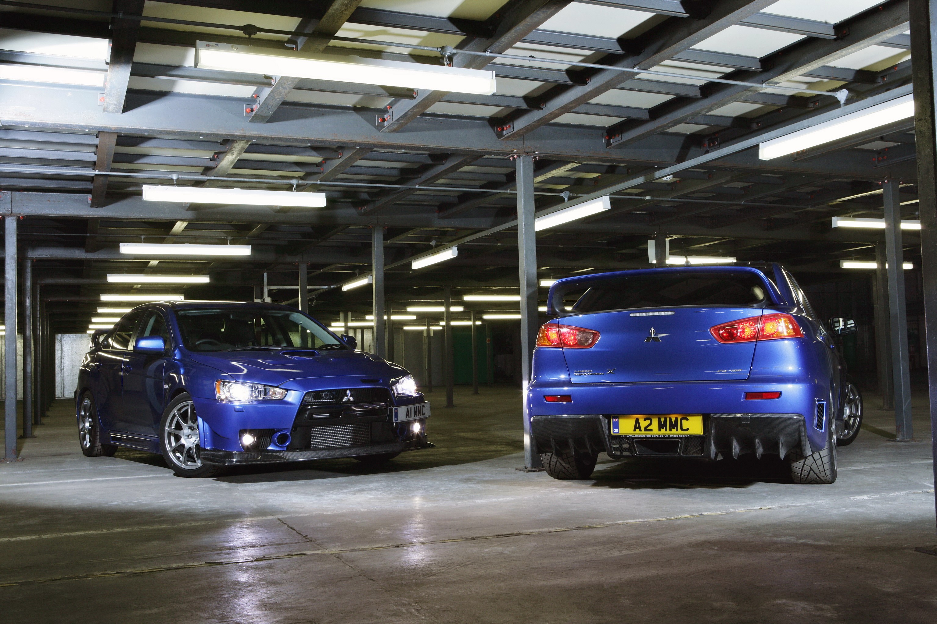 Two blue Mitsubishi Lancer Evolution X FQ-400 cars in a parking garage HD Wallpaper