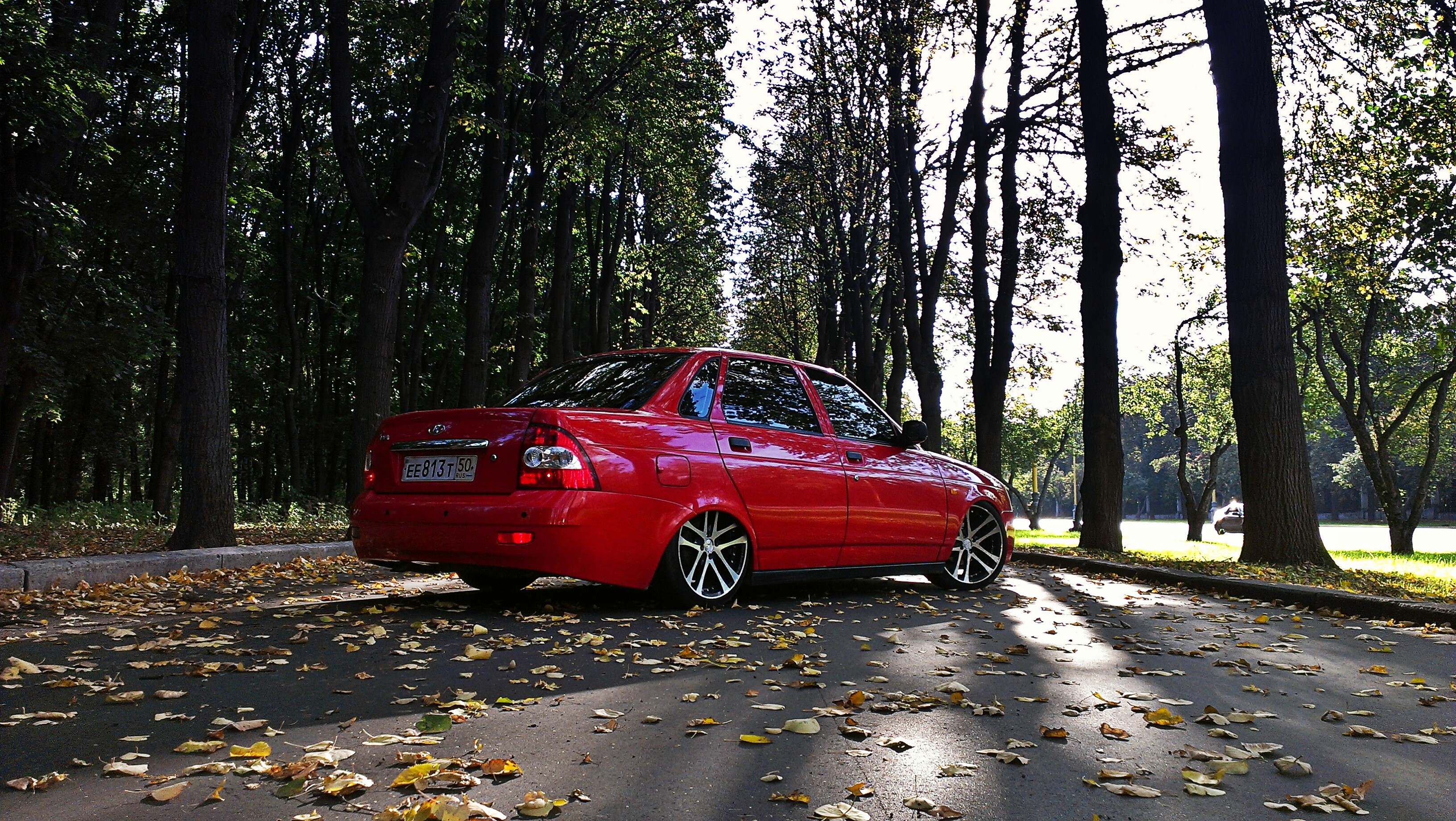 Red Lada 2170 car in autumn park with fallen leaves HD Wallpaper