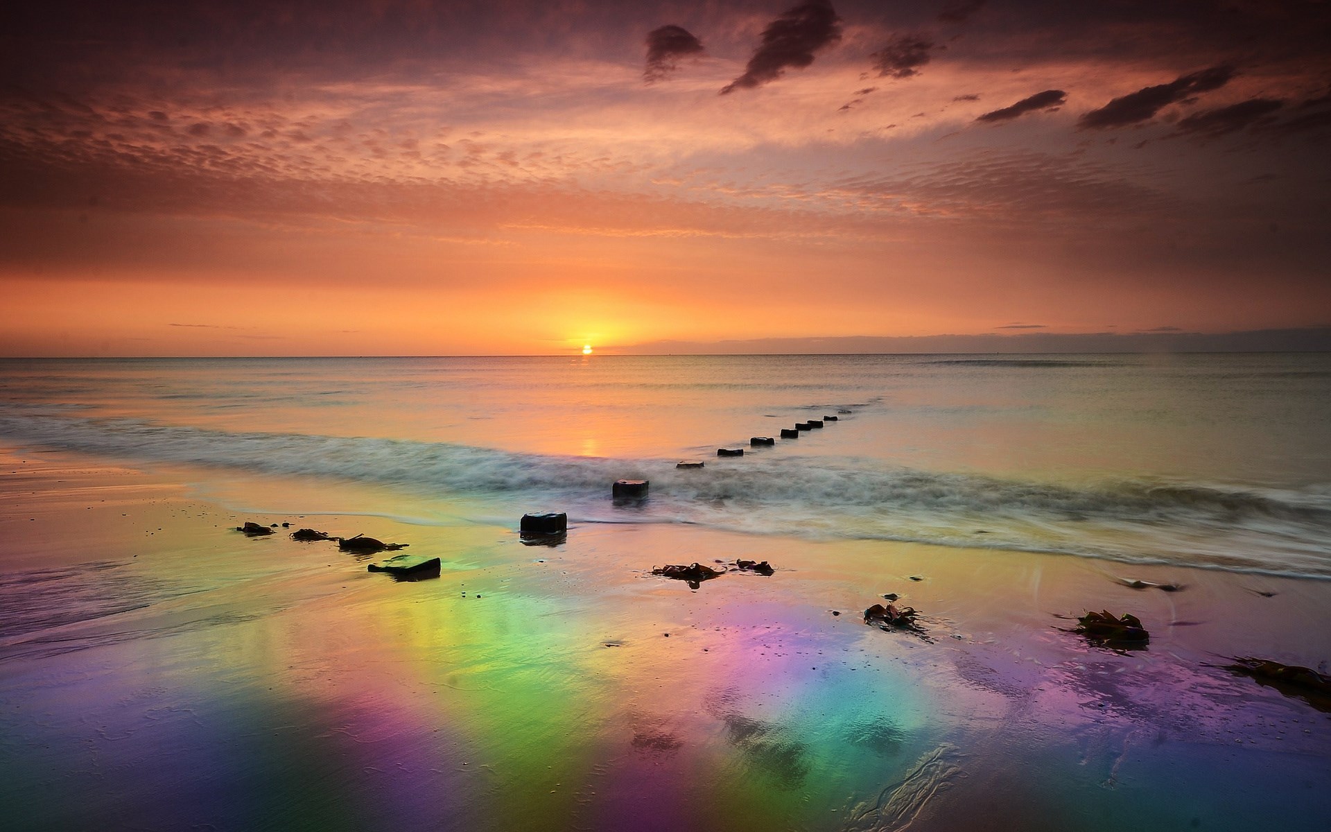 Rainbow beach at sunset with wooden posts HD Wallpaper