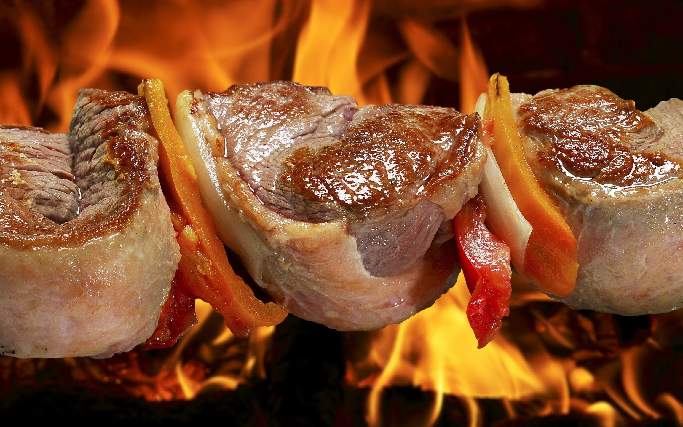 Meat skewers cooking over an open fire HD Wallpaper