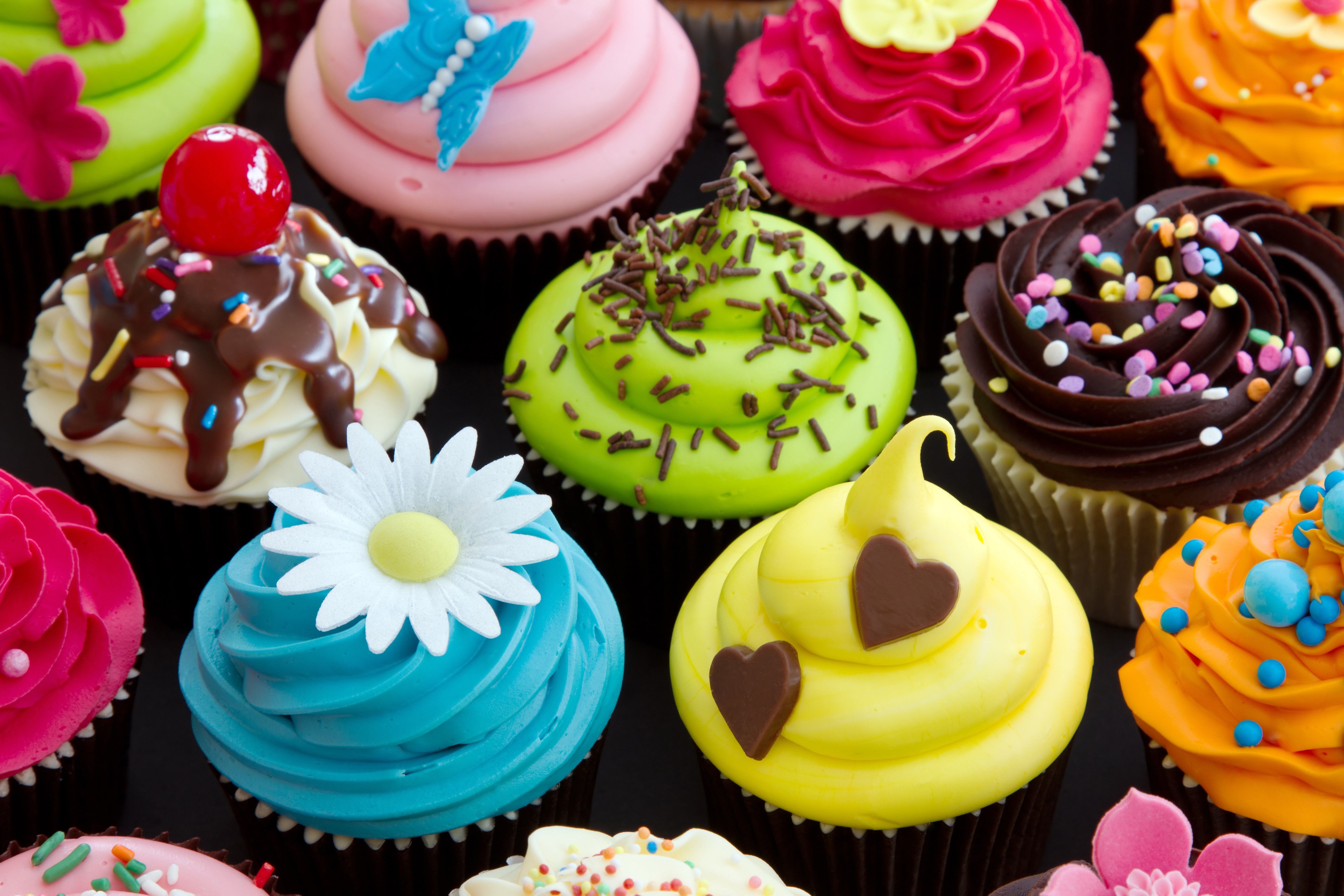 Assortment of colorful cupcakes with various decorations HD Wallpaper