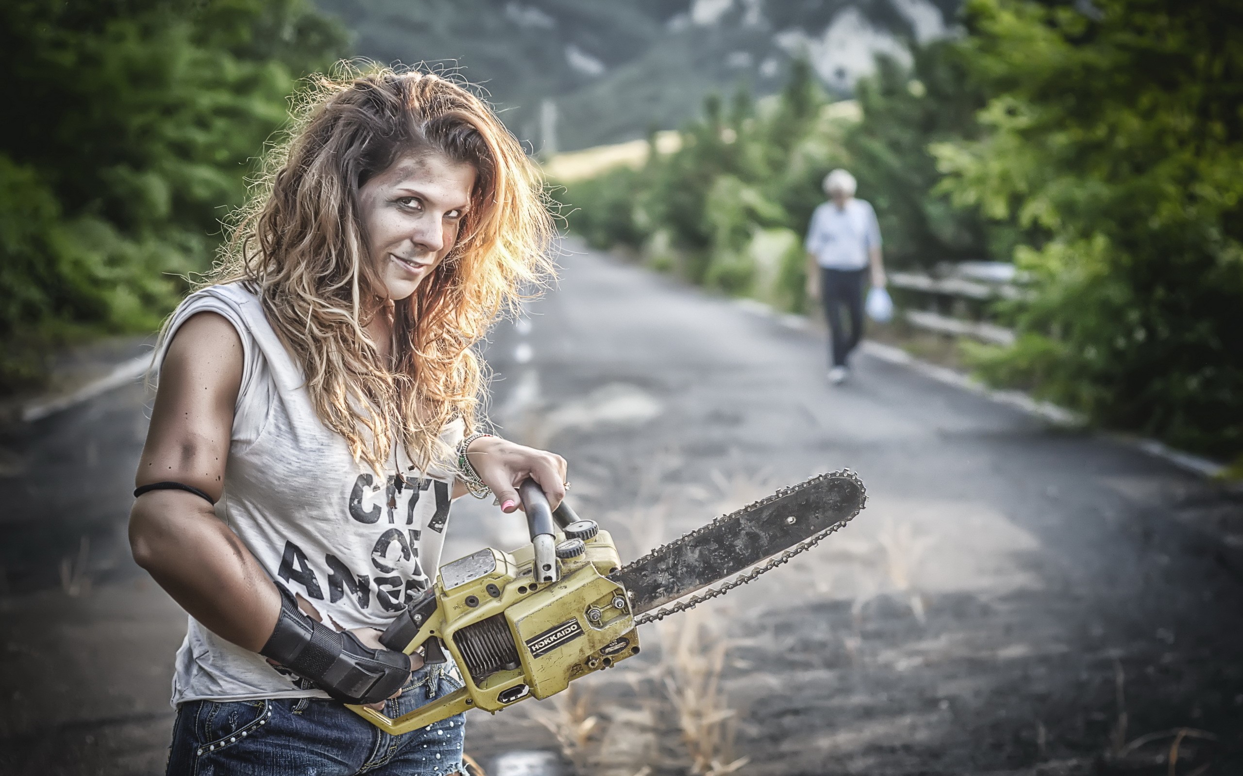 Woman with chainsaw on a road HD Wallpaper