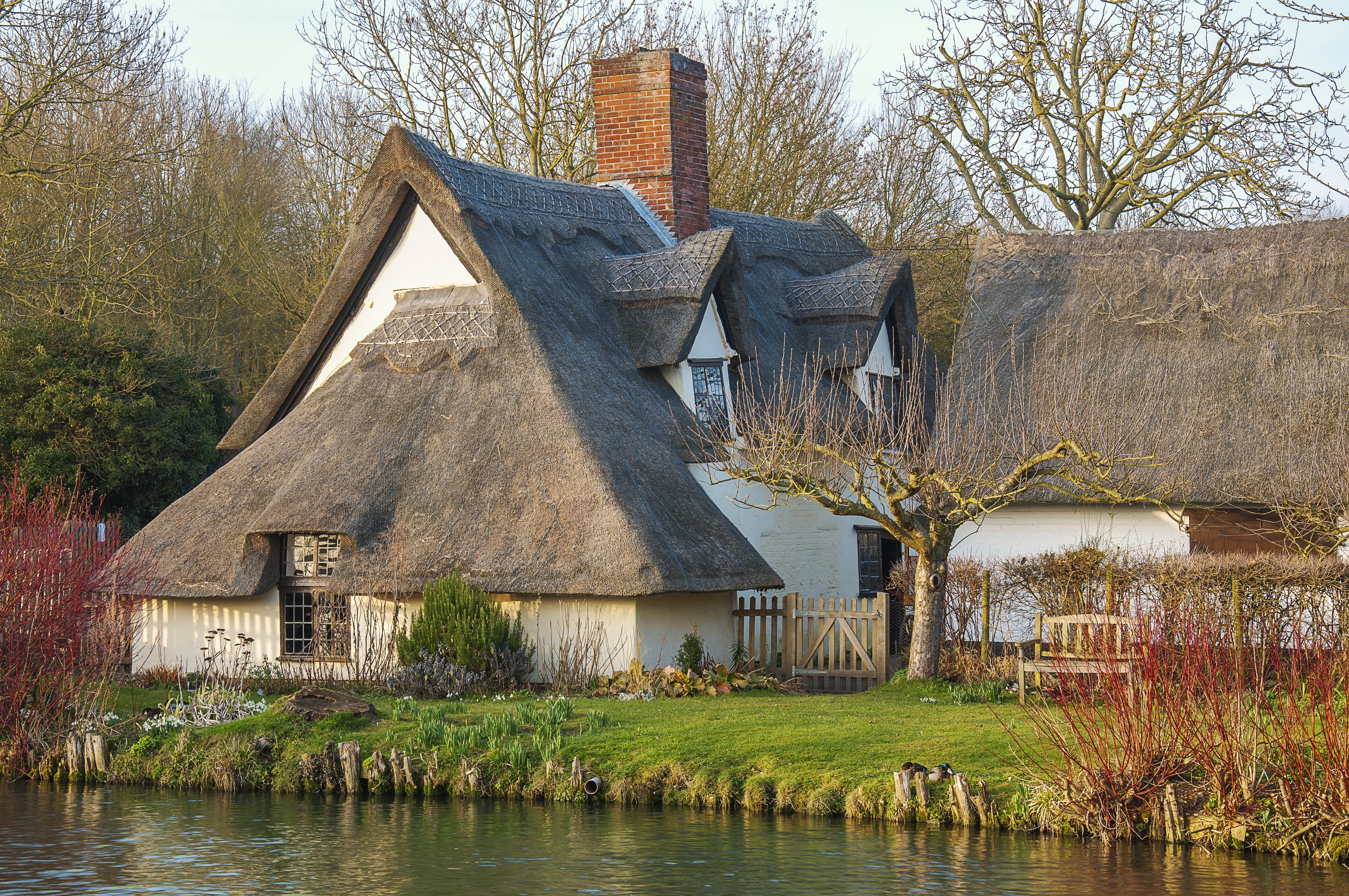 Thatched roof cottages by a river in East Bergholt, England HD Wallpaper