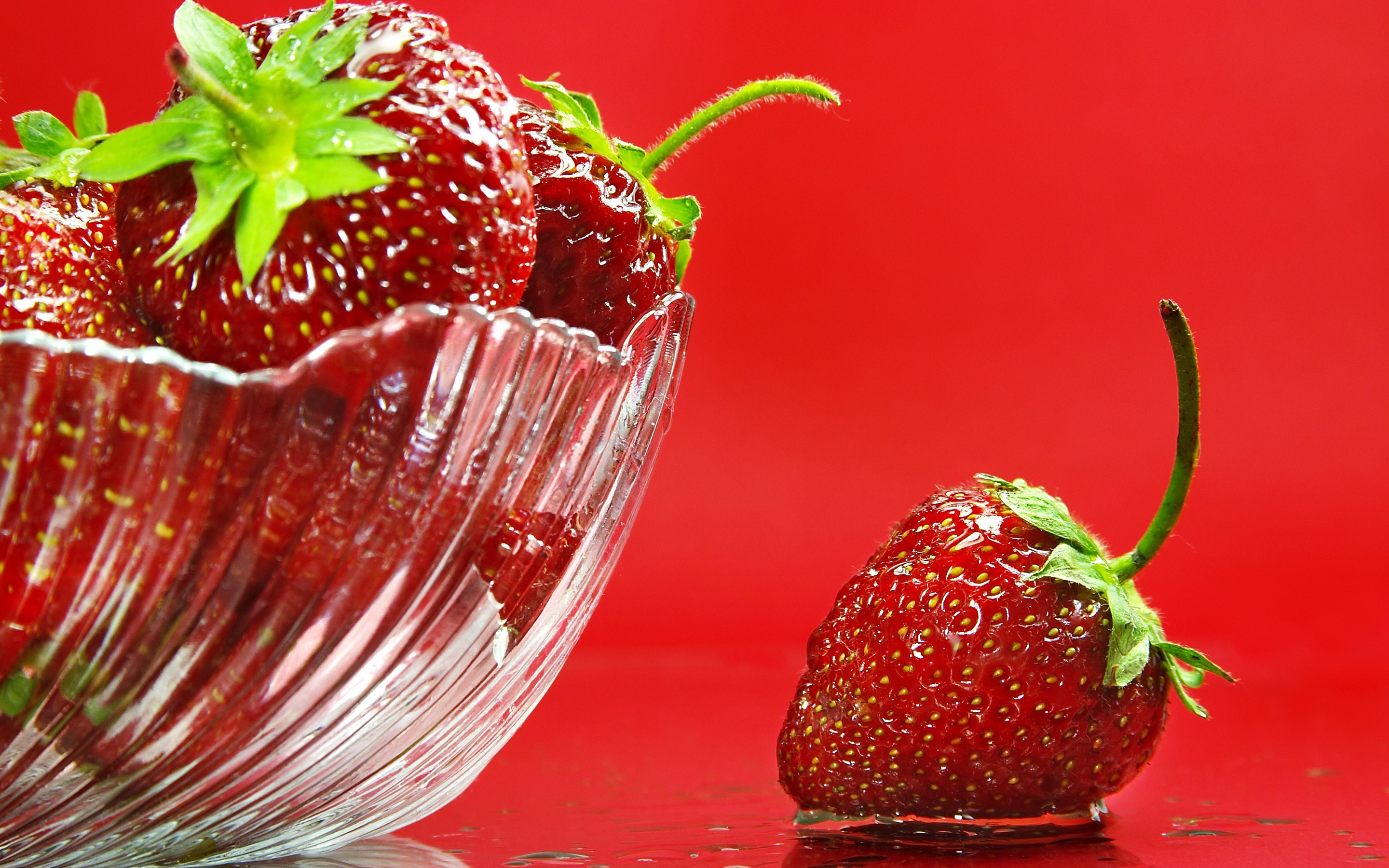 Strawberries in a glass bowl and on a red surface HD Wallpaper