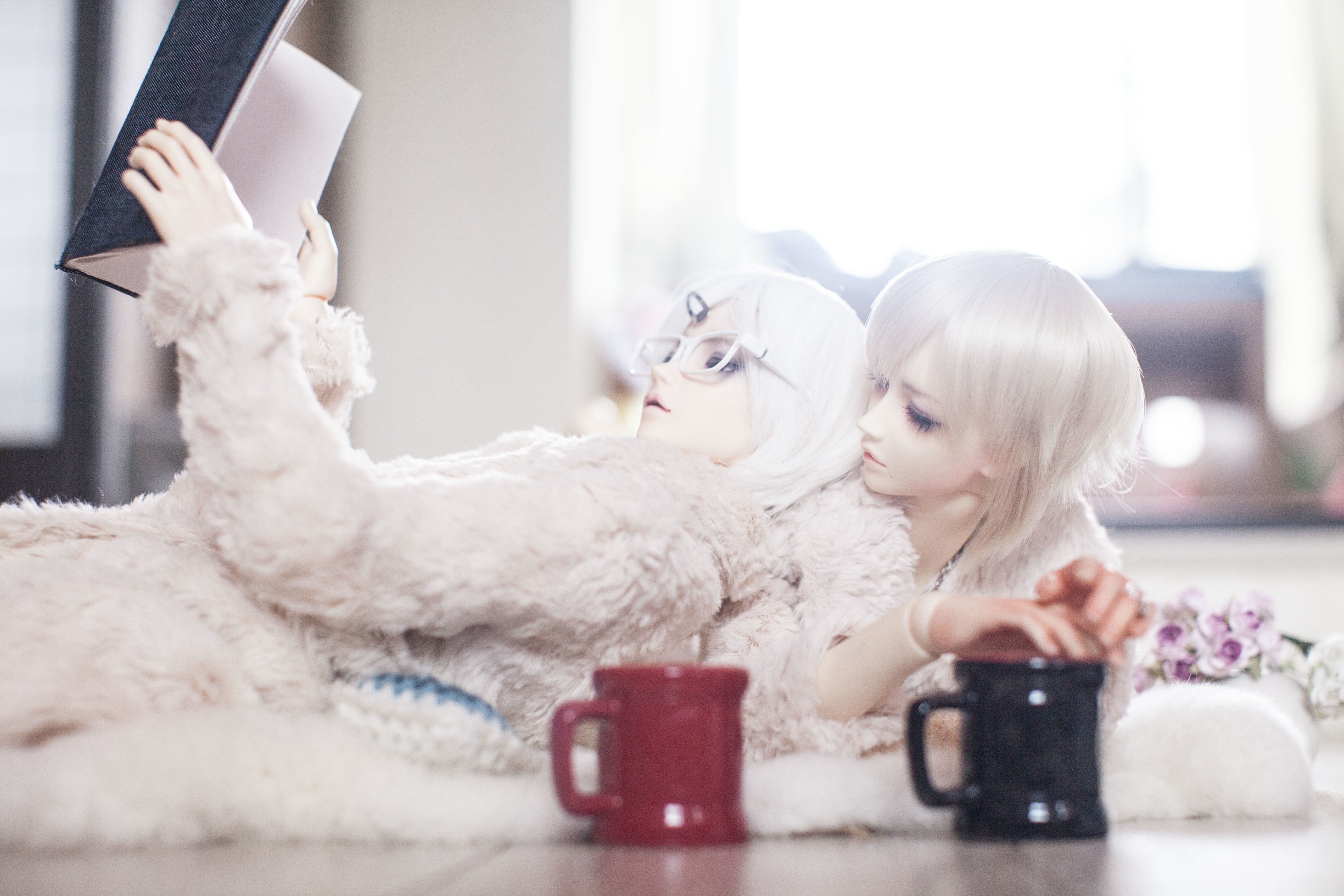 Two dolls with cups and a book HD Wallpaper