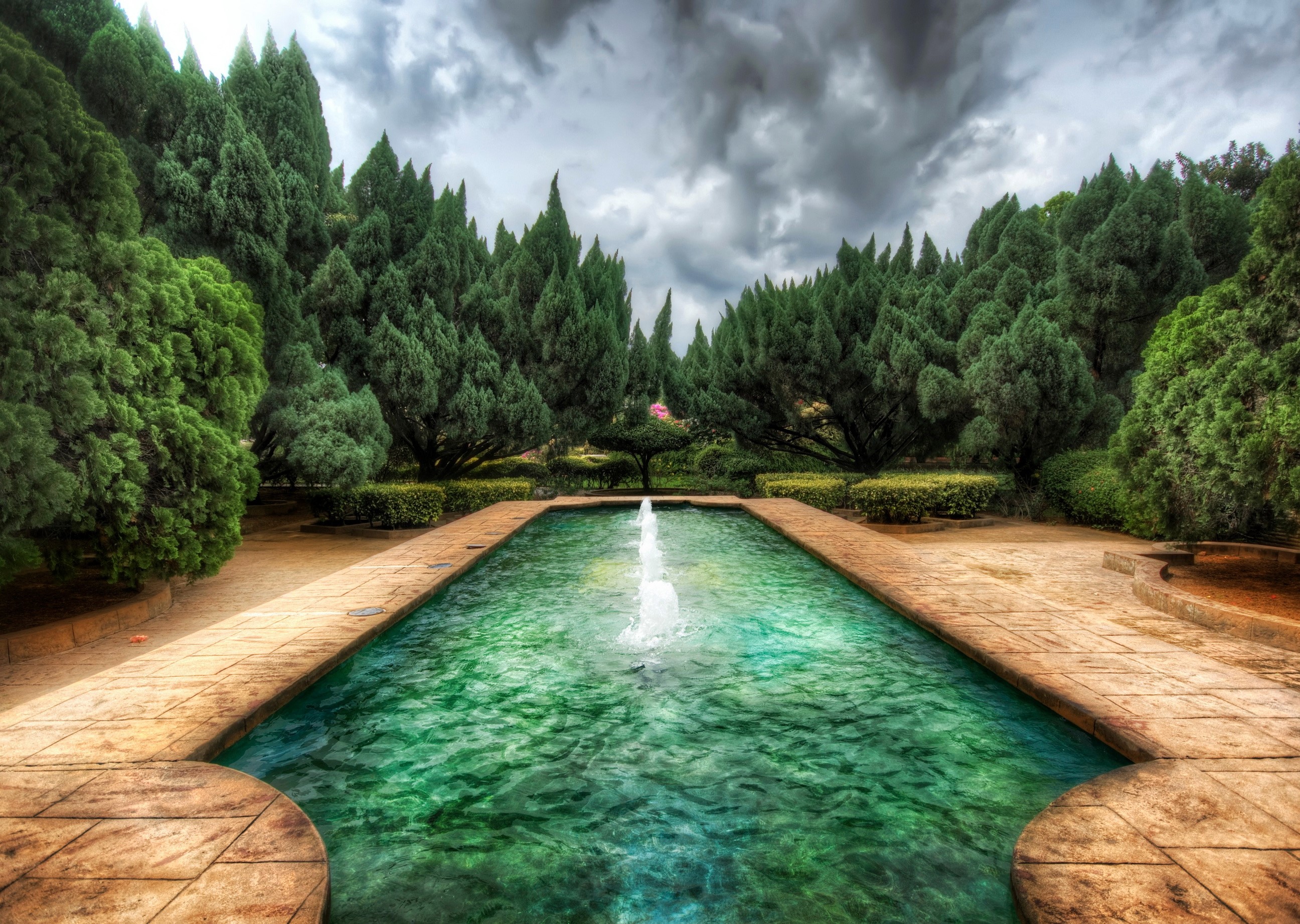 Rectangular fountain with trees and cloudy sky HD Wallpaper