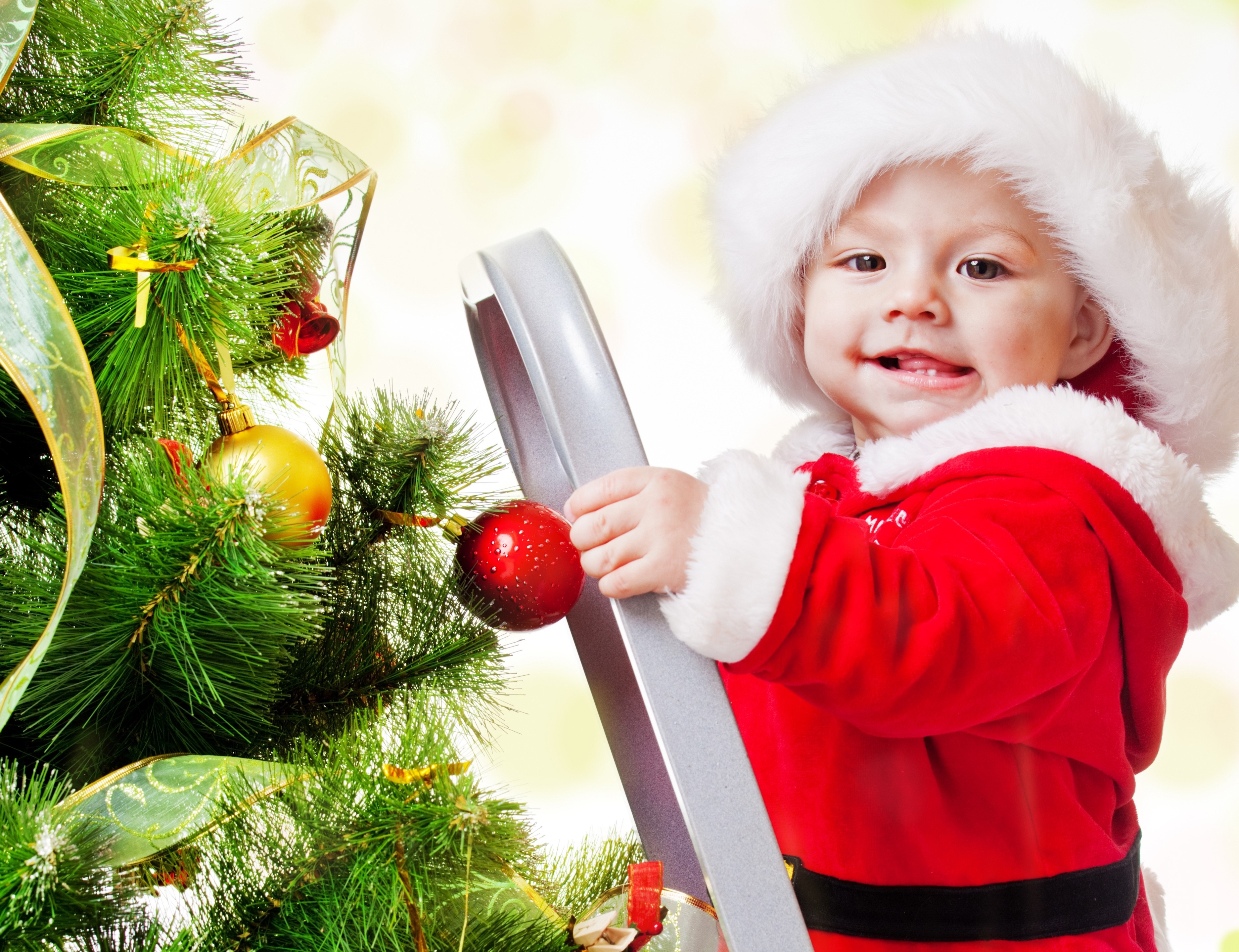 Baby in Santa costume decorating a Christmas tree HD Wallpaper
