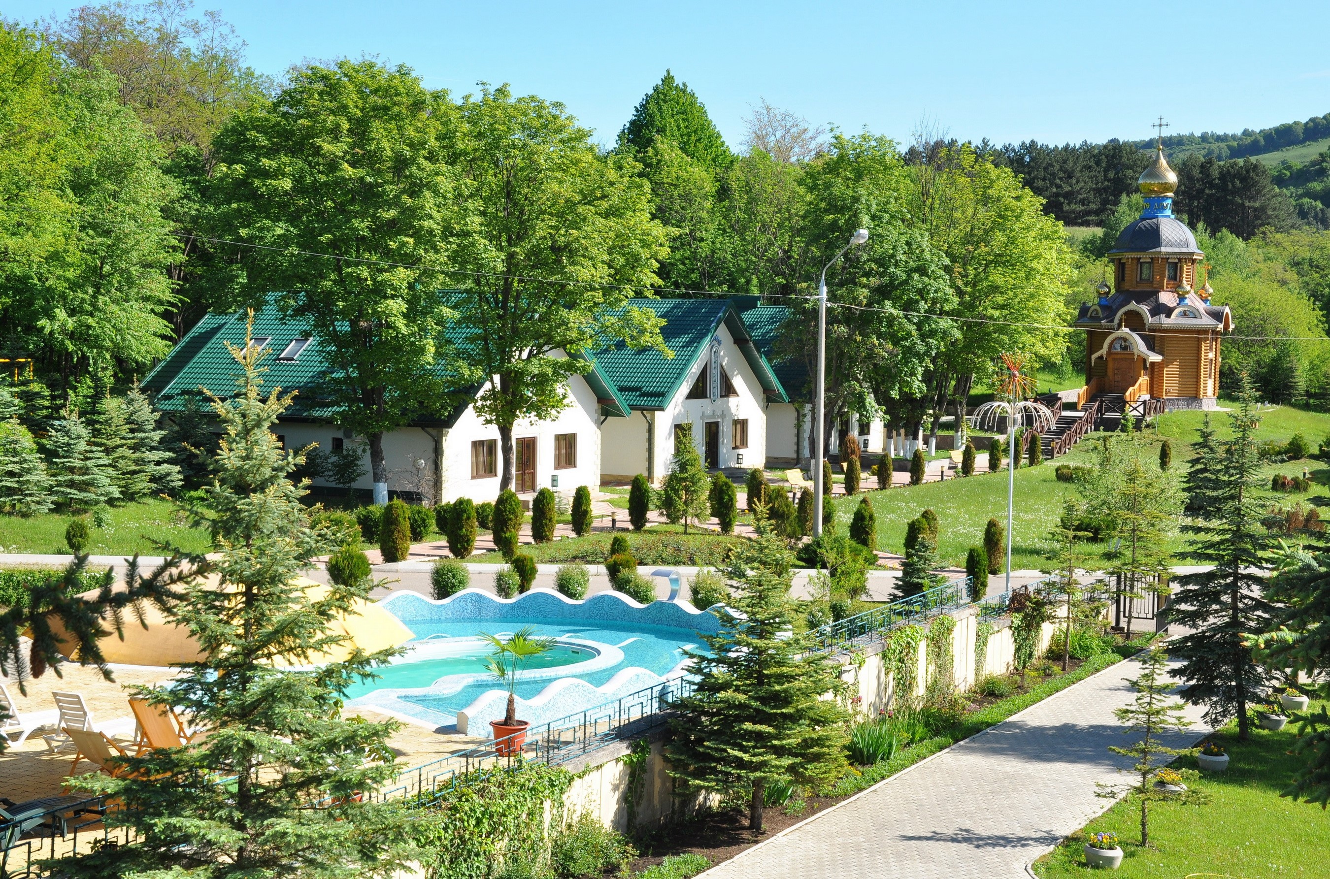 Houses and chapel in a green landscape with a pool HD Wallpaper