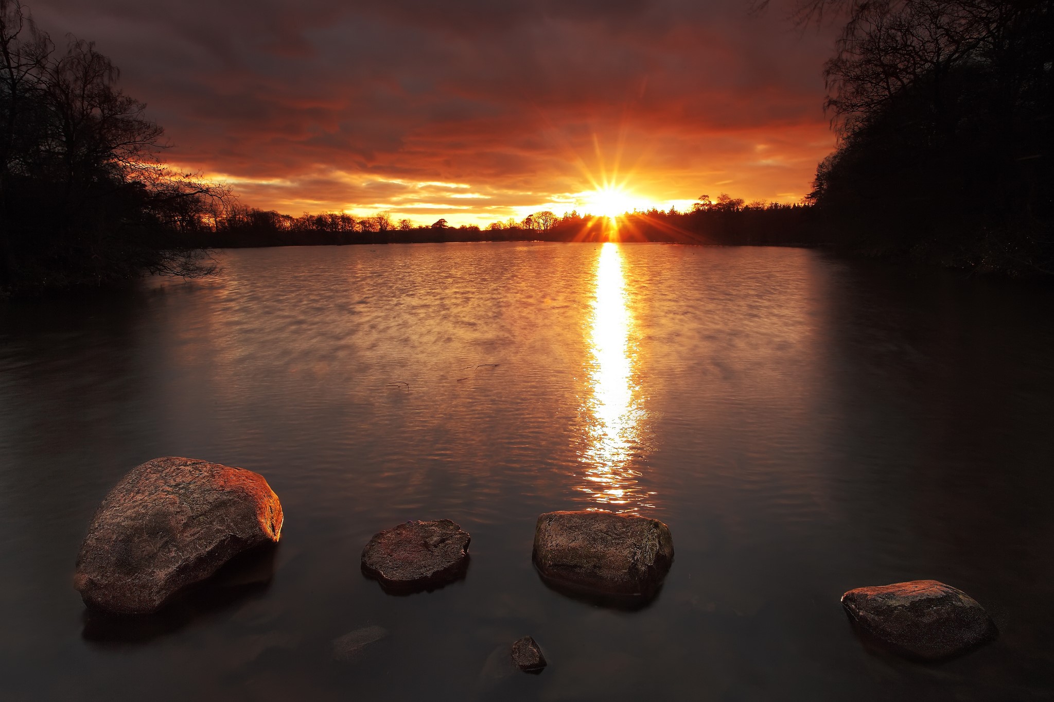 Sunset over a lake with stones in the foreground HD Wallpaper