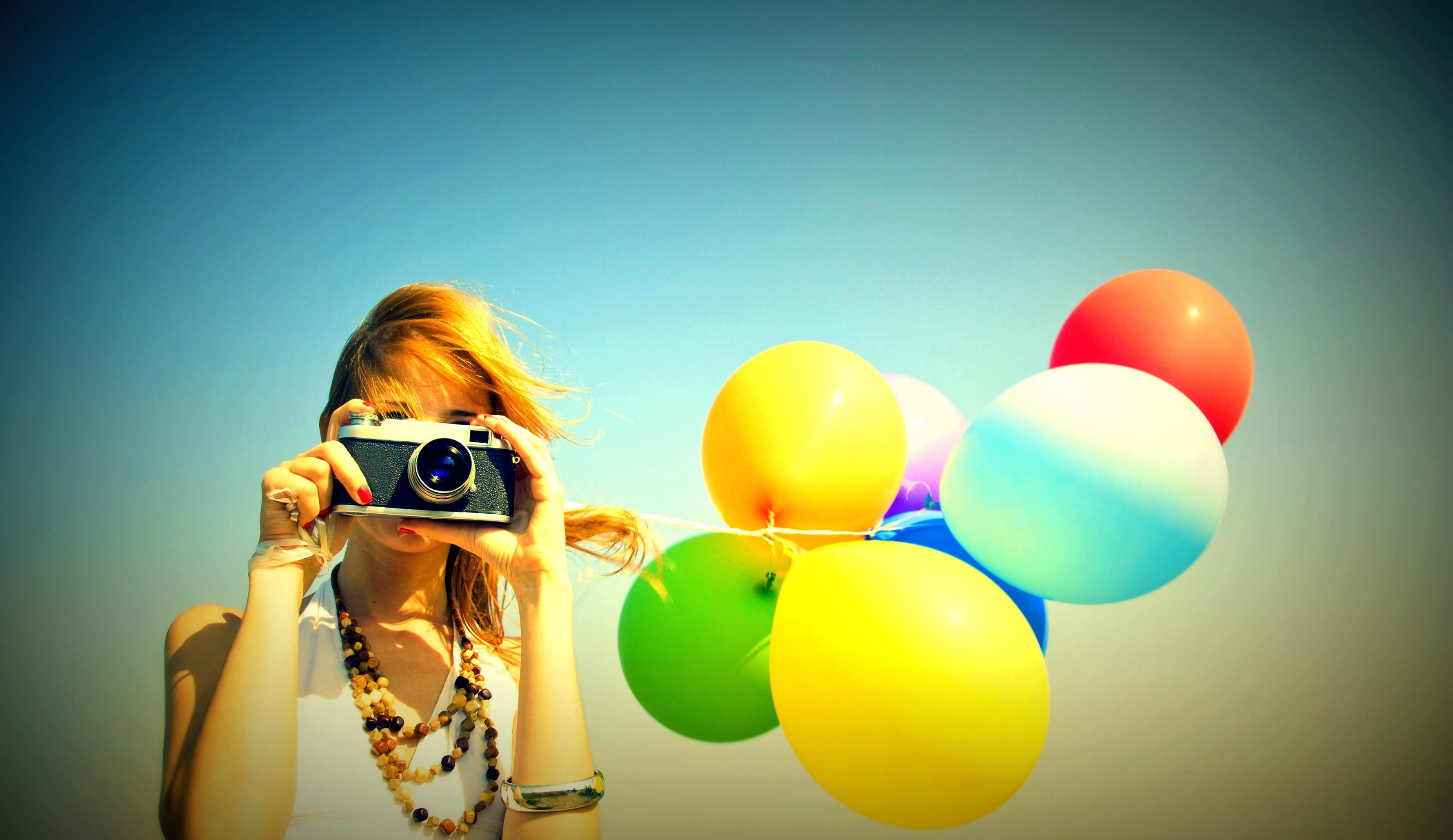 Woman holding a camera and colorful balloons HD Wallpaper