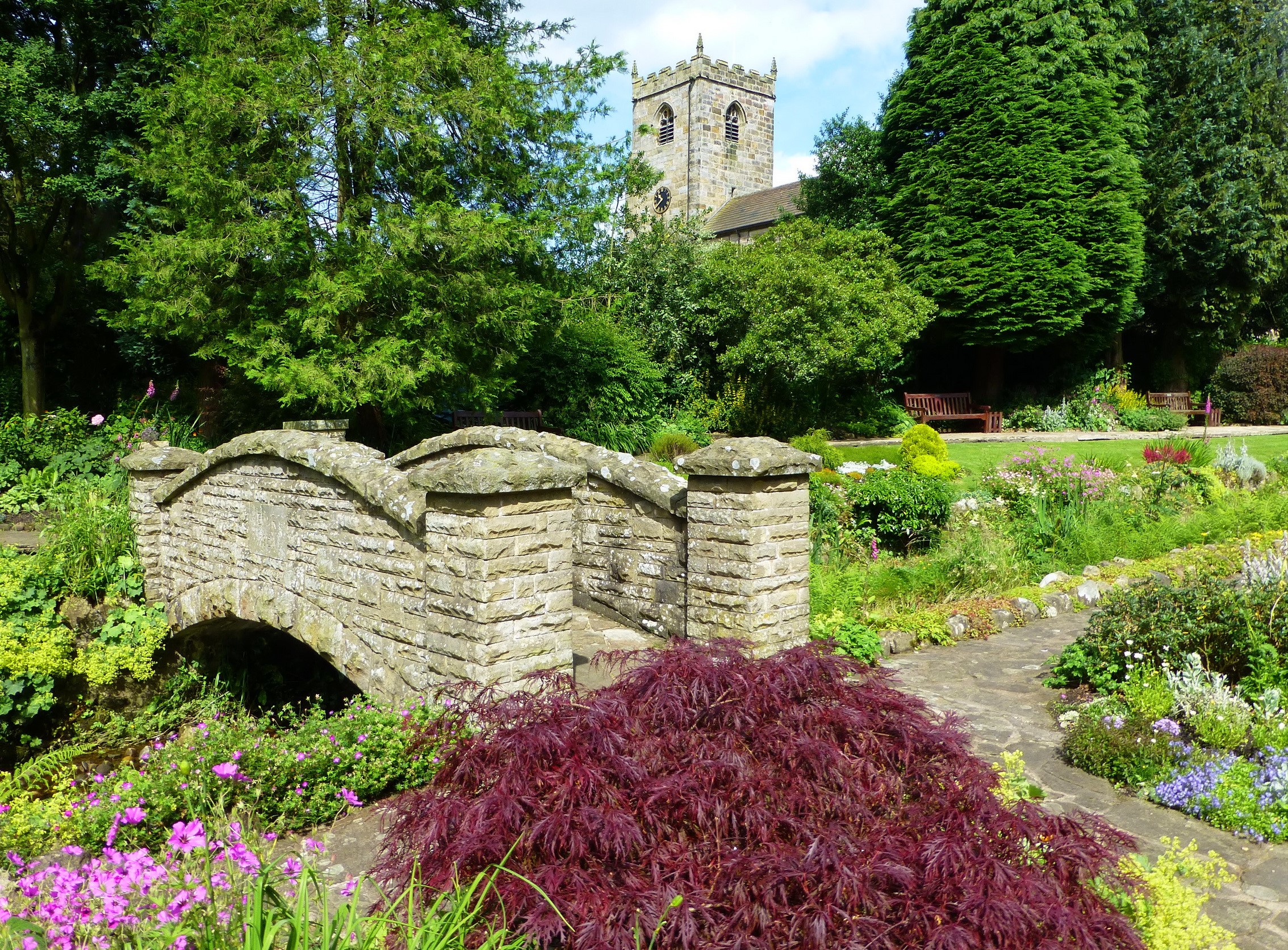 Stone bridge in a park with a church tower in Waddington, England HD Wallpaper