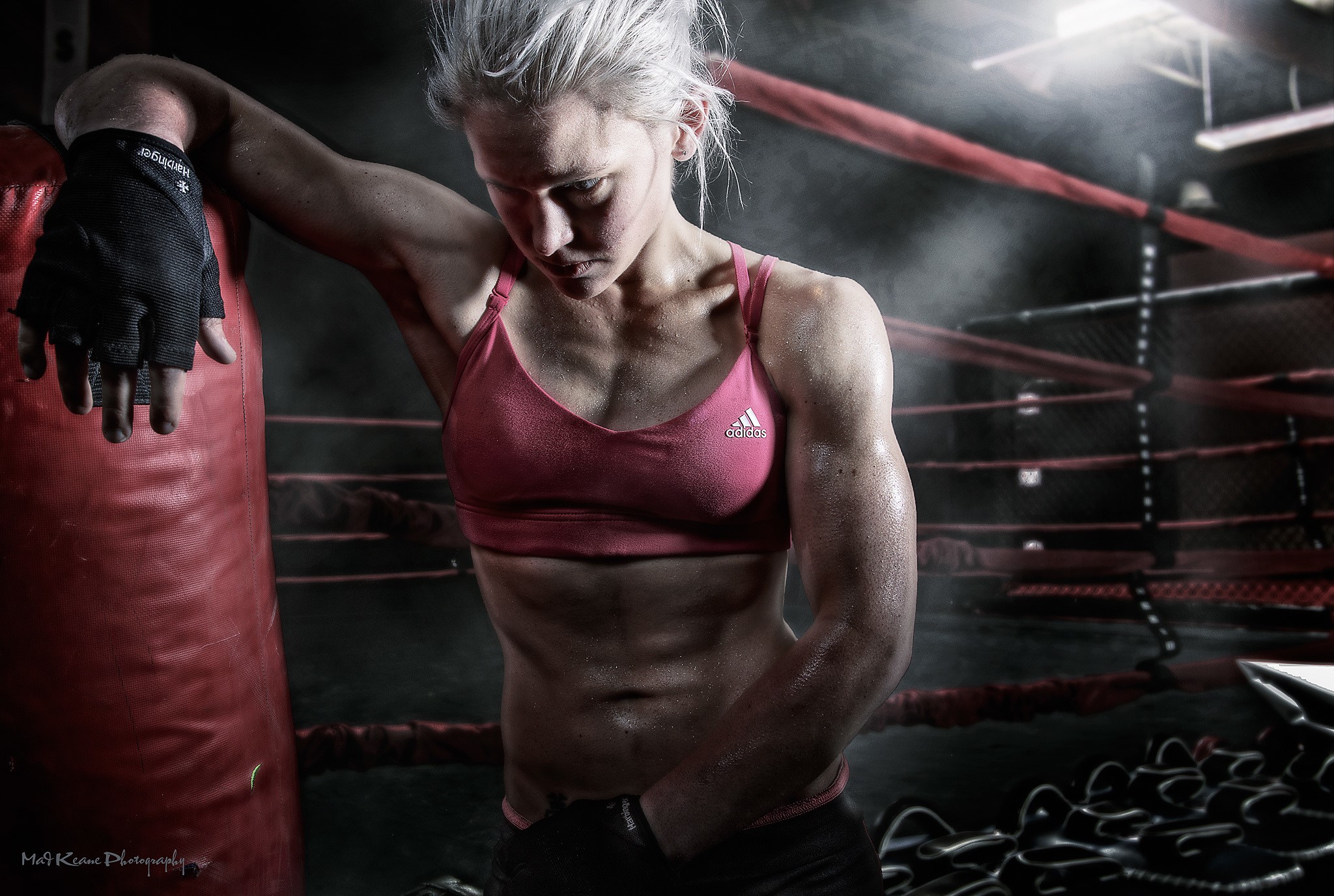 Female boxer leaning on punching bag in boxing ring HD Wallpaper