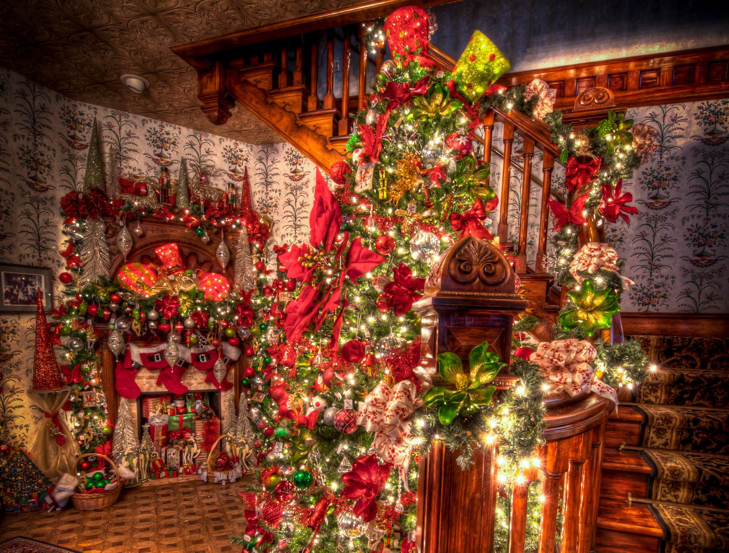 Christmas decorations in a home with a fireplace and staircase HD Wallpaper