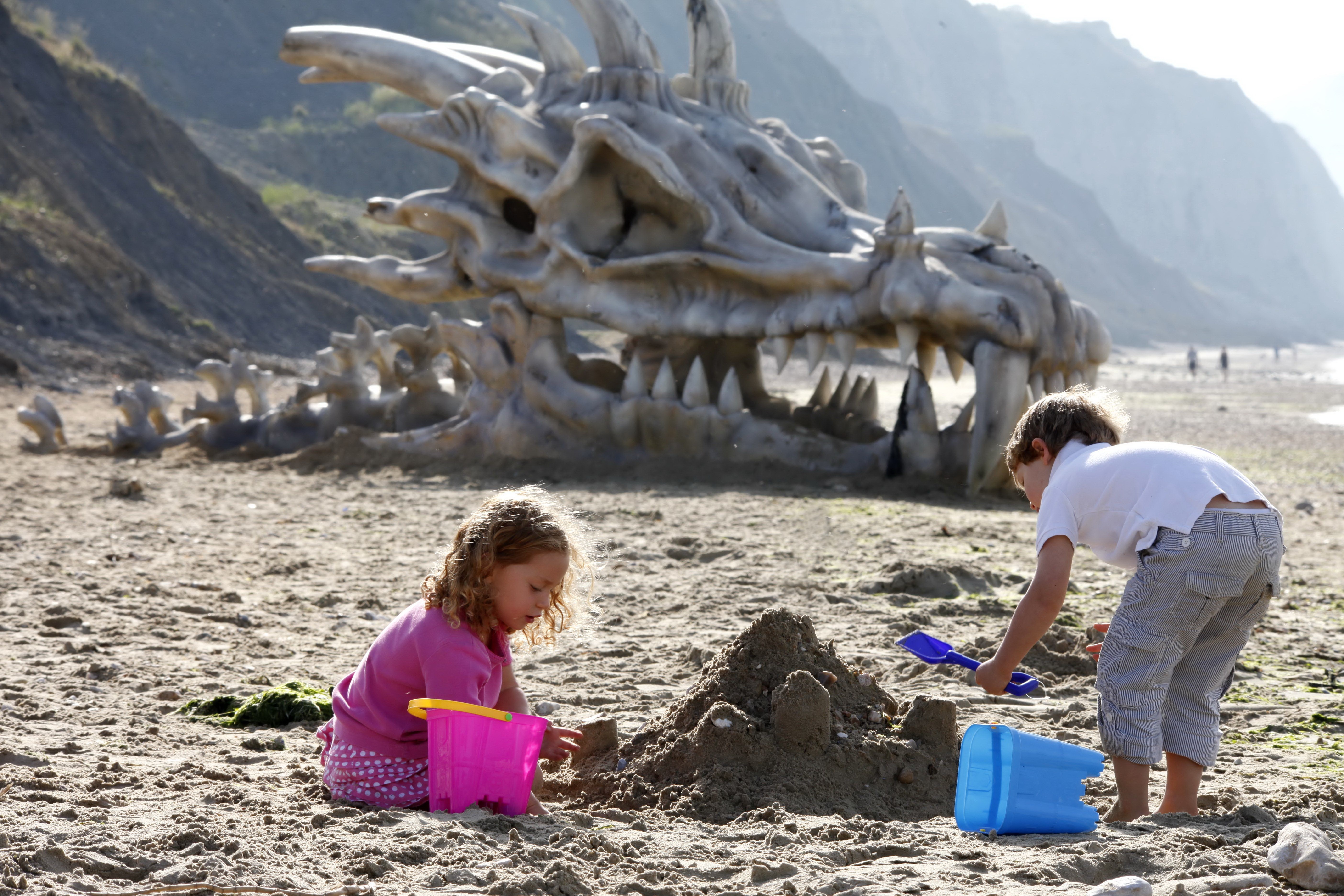 Children playing on a beach with a dragon skeleton HD Wallpaper