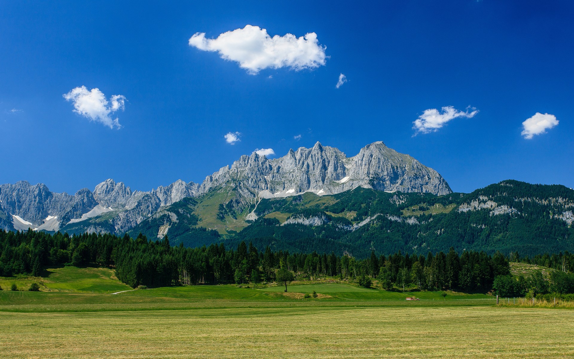 Mountain range with green fields and blue sky HD Wallpaper