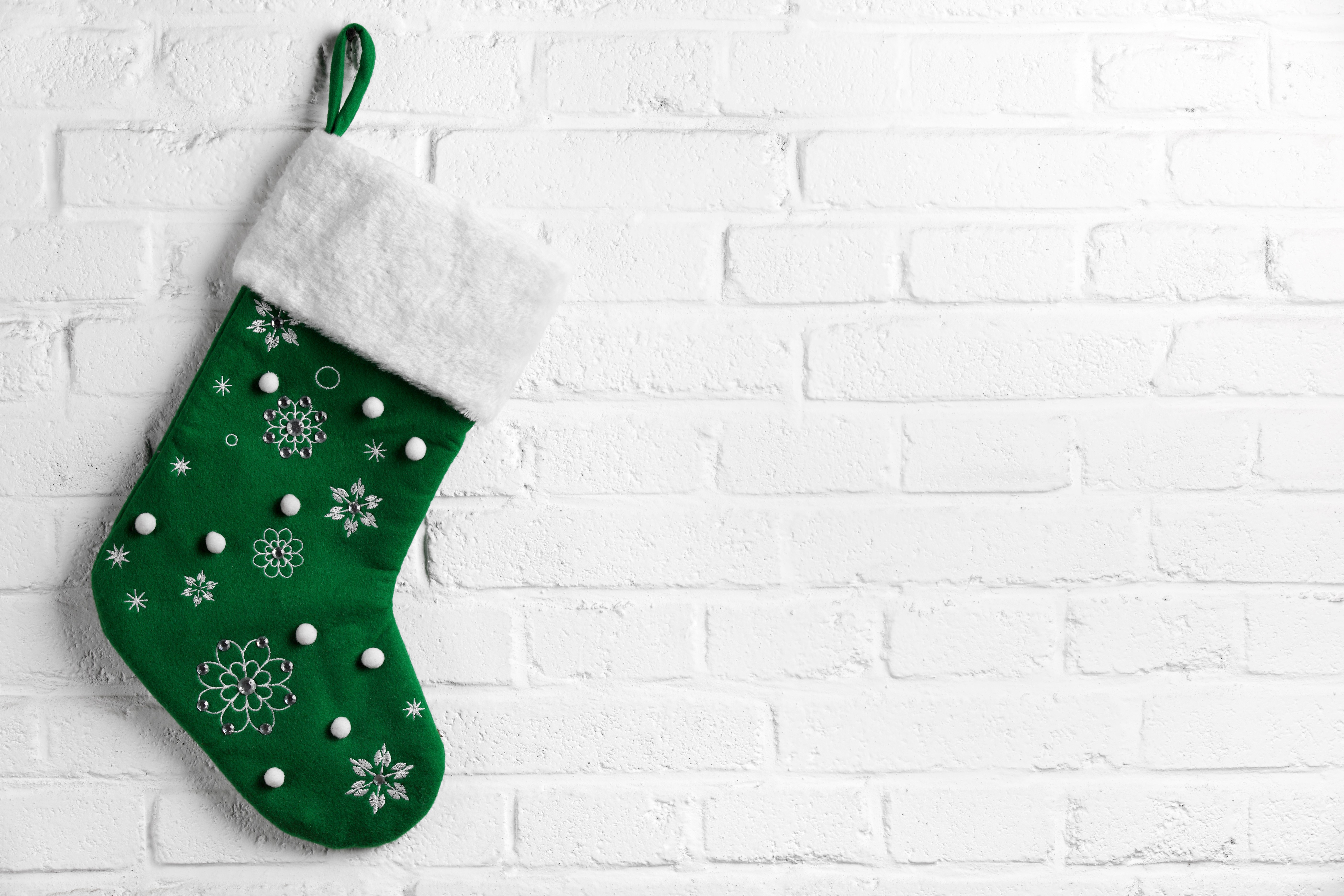Green Christmas stocking with snowflakes on a white brick wall HD Wallpaper