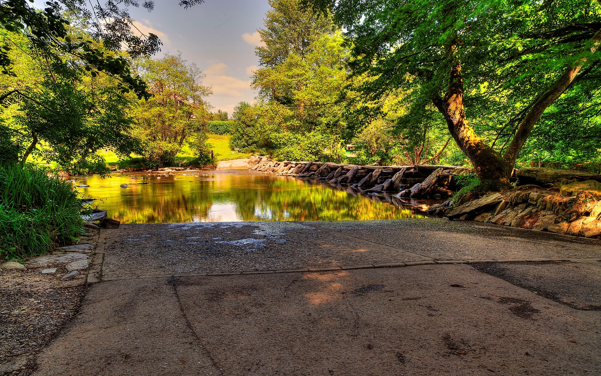 Stone dam across a river with trees and a boat ramp HD Wallpaper