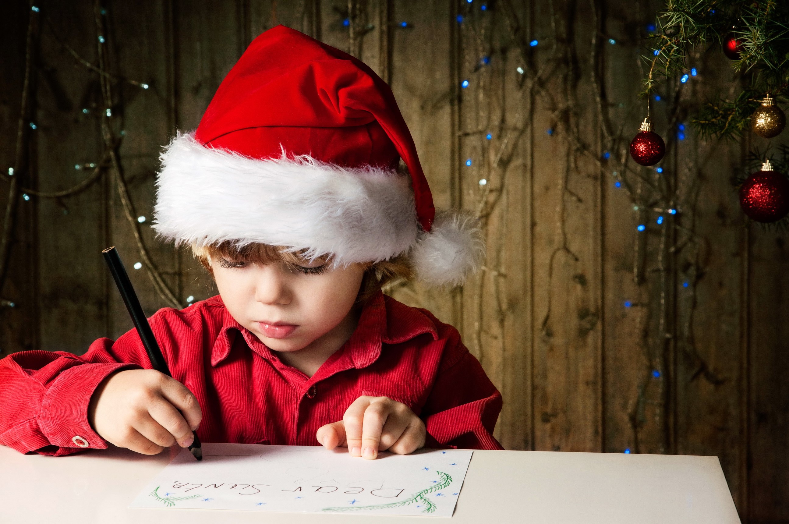 Boy in Santa hat writing a letter to Santa HD Wallpaper