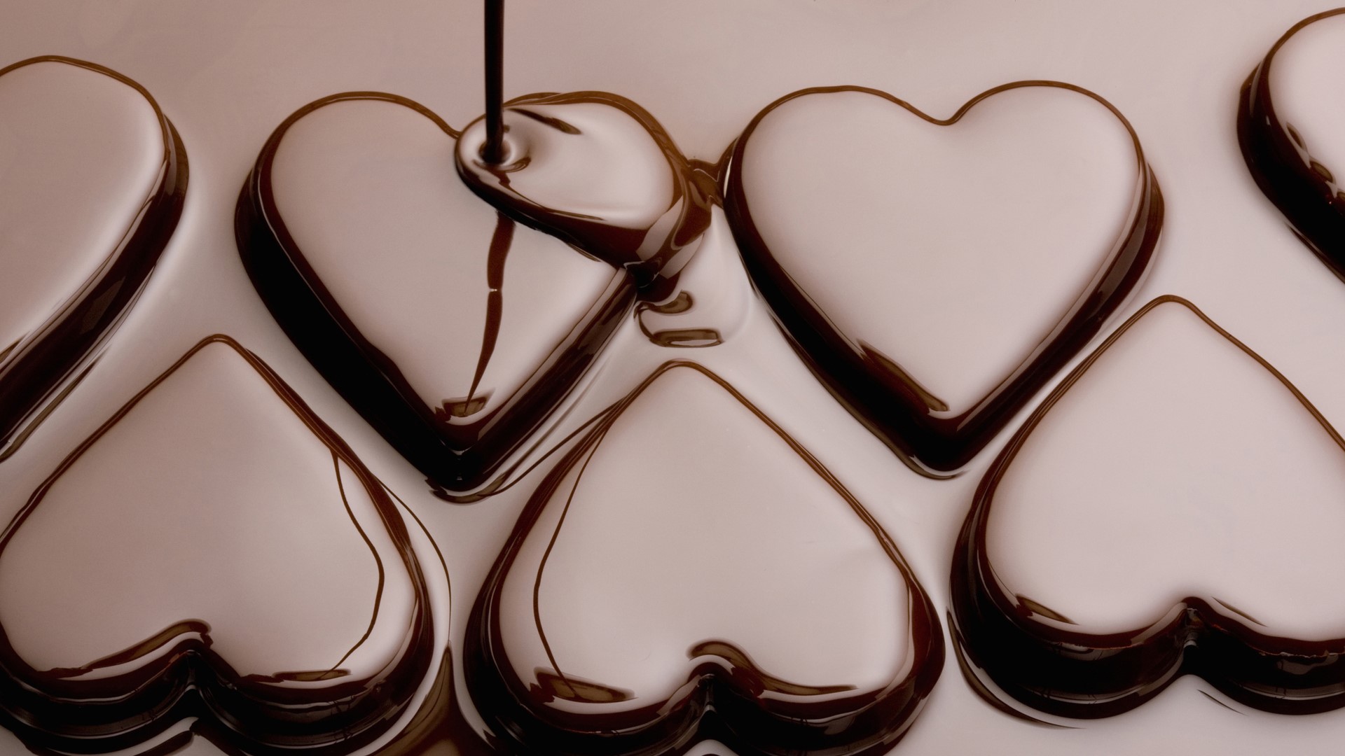 Chocolate being poured into heart-shaped molds HD Wallpaper