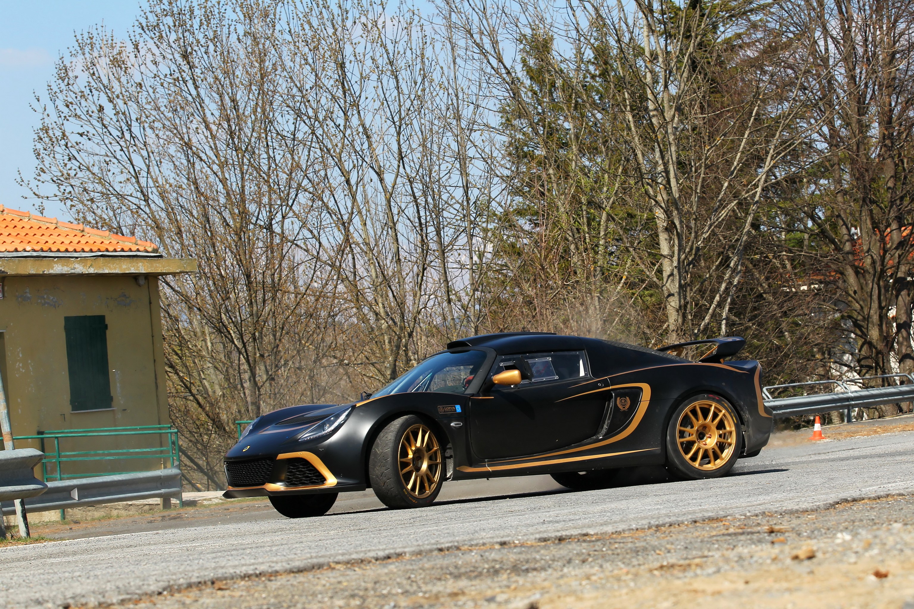Black Lotus Exige R-GT rally car with gold accents HD Wallpaper