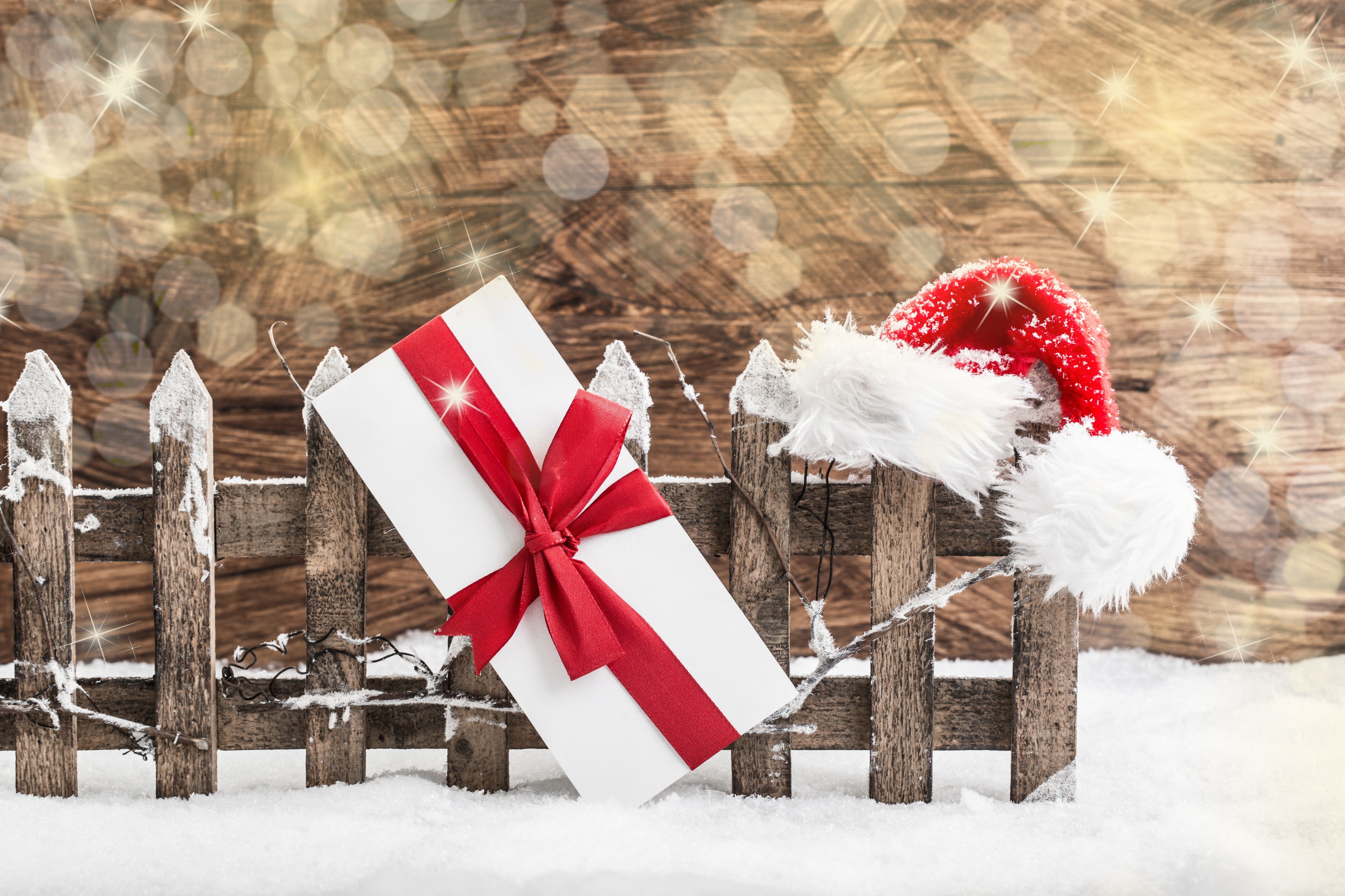 Christmas gift and Santa hat on a snowy fence HD Wallpaper