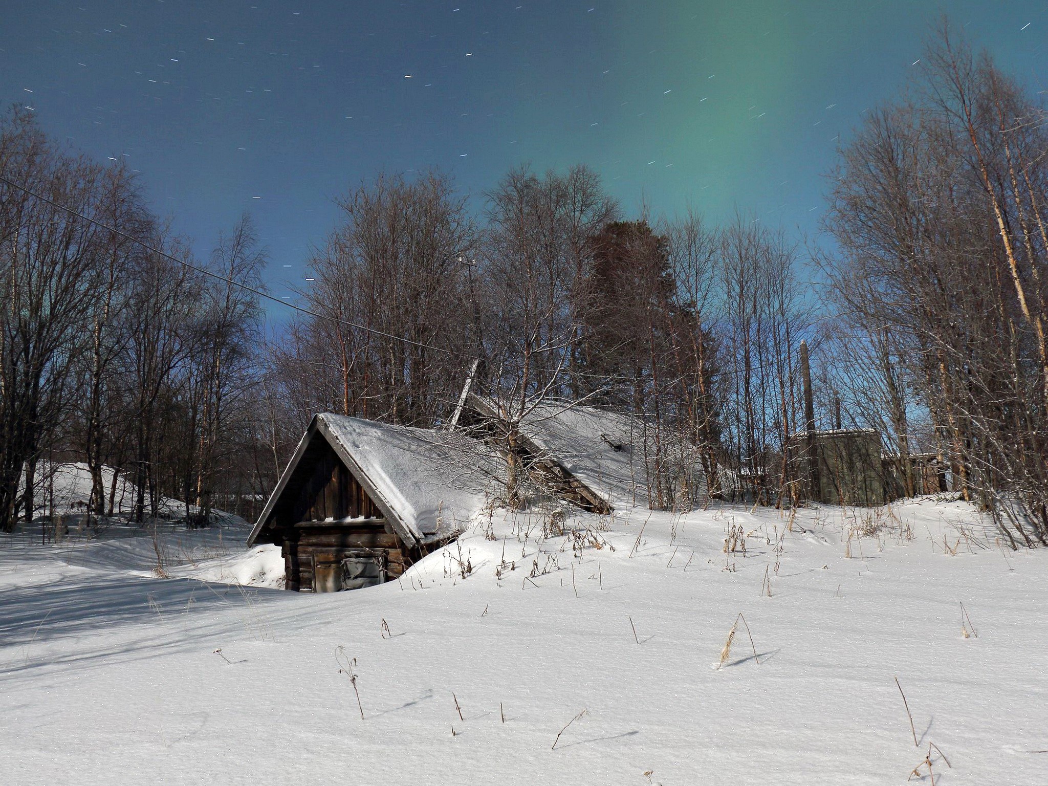Snowy landscape with abandoned wooden structure and aurora borealis HD Wallpaper