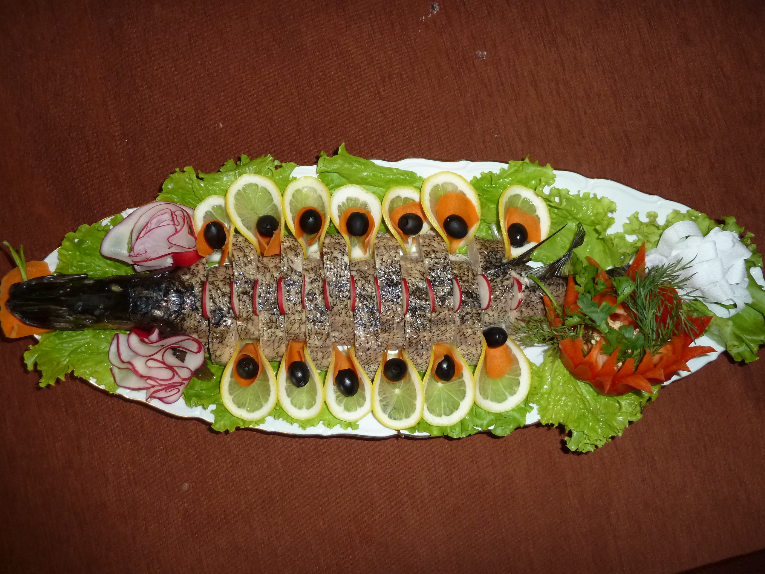 Whole fish platter with lemon, olives, and radish garnish HD Wallpaper