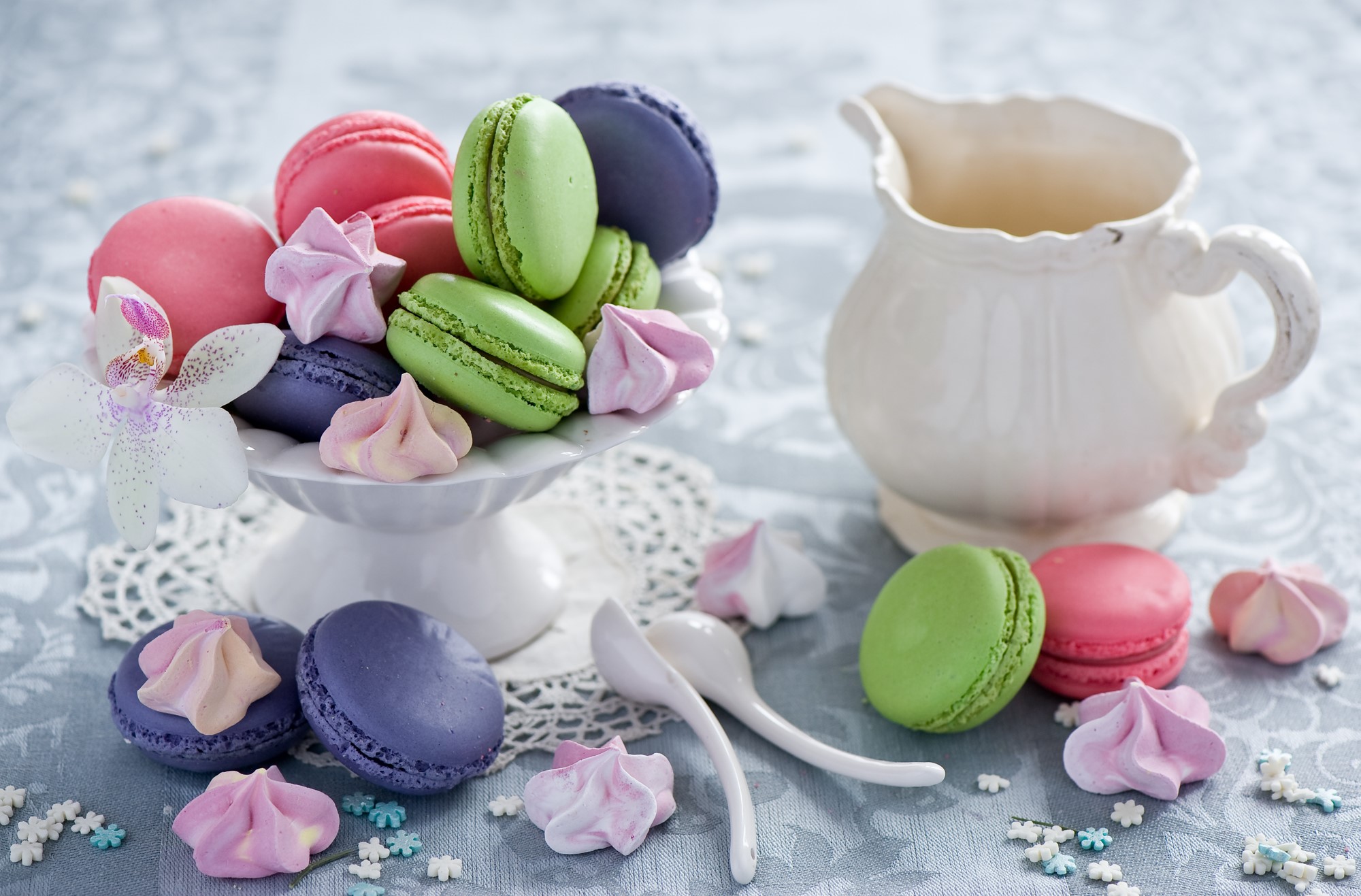 Colorful macarons and meringues on a white cake stand with a pitcher HD Wallpaper