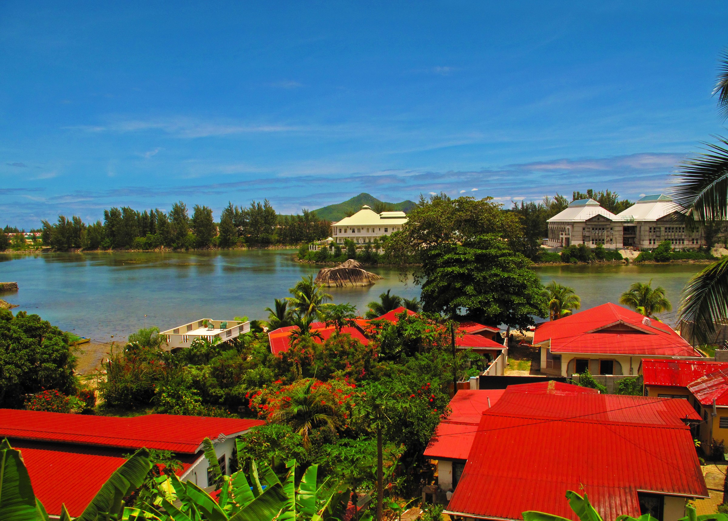 Tropical island with red-roofed houses and a bay HD Wallpaper