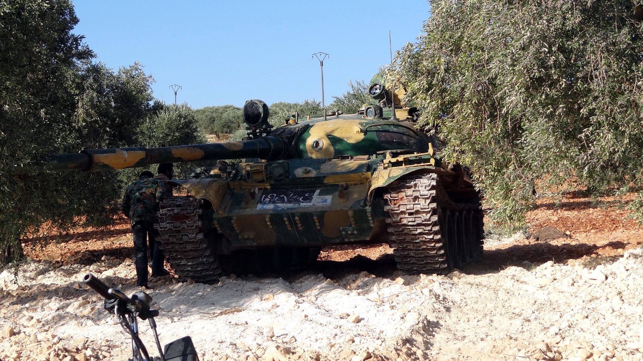Camouflaged tank in an olive grove with two soldiers HD Wallpaper