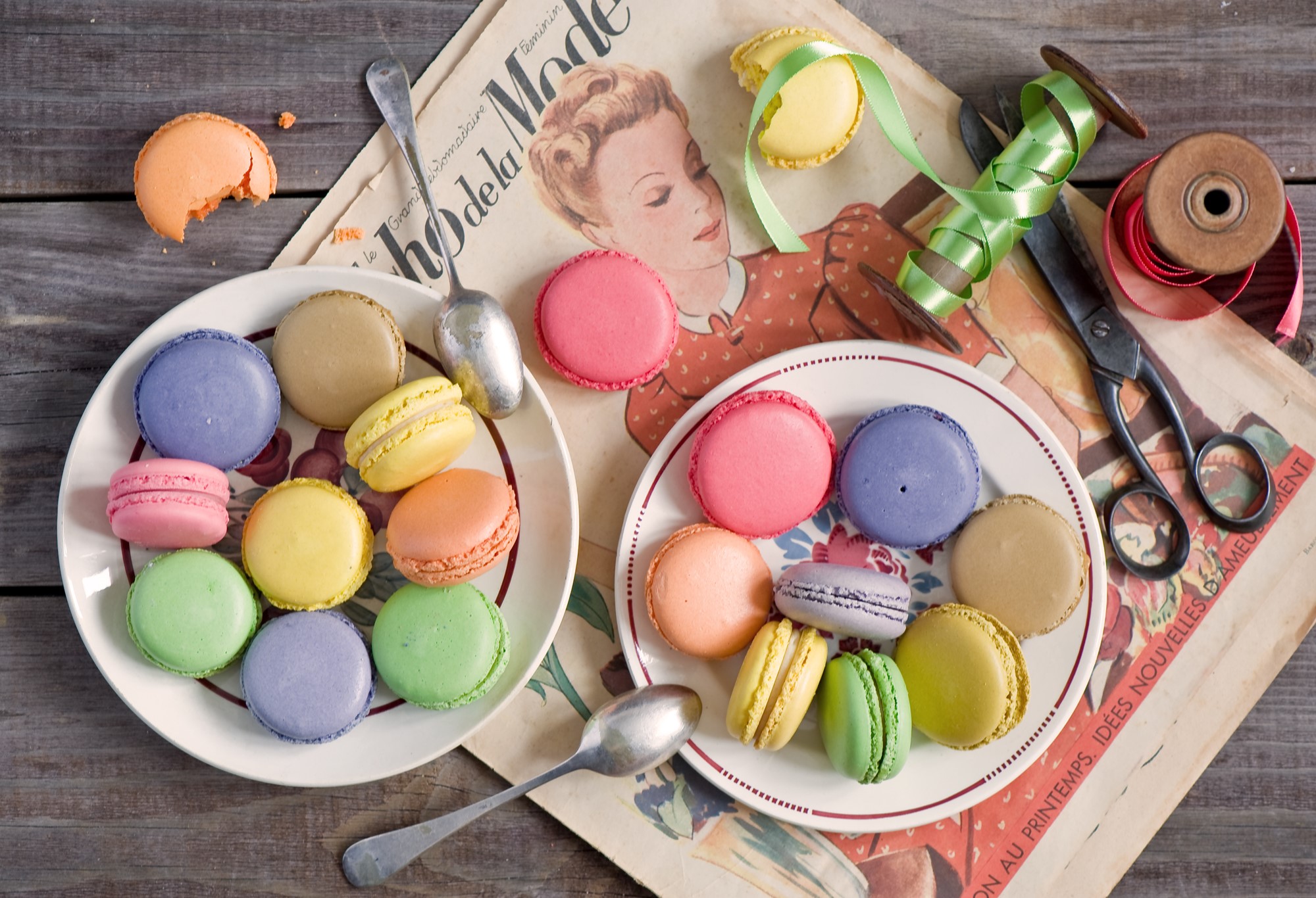Macarons on plates with vintage magazine and scissors HD Wallpaper