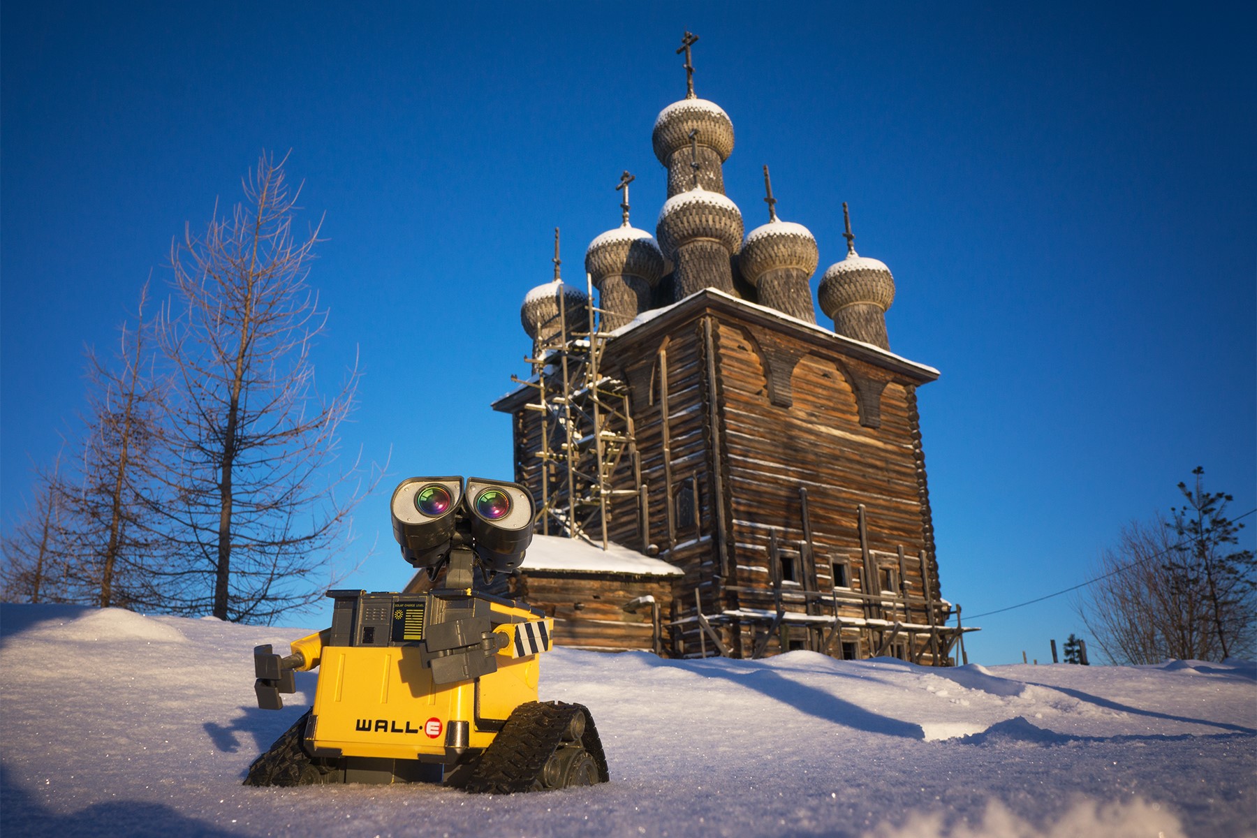 WALL·E toy in front of a wooden church in winter HD Wallpaper