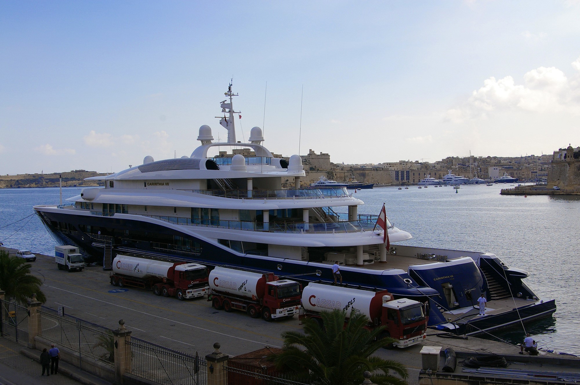 Carinthia VII Yacht docked at a marina with fuel trucks HD Wallpaper