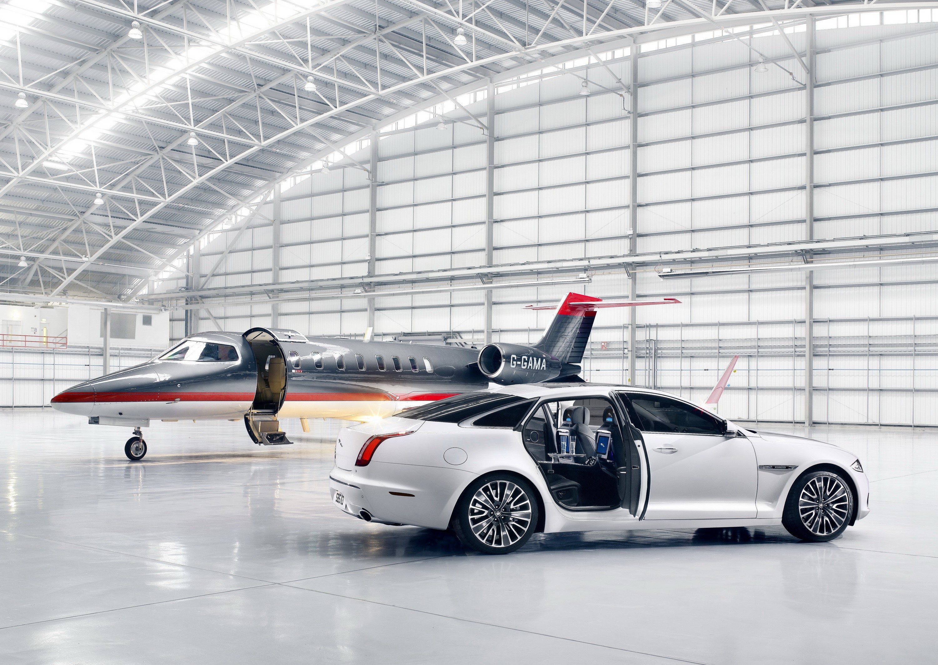 Jaguar XJ Ultimate and private jet in hangar HD Wallpaper
