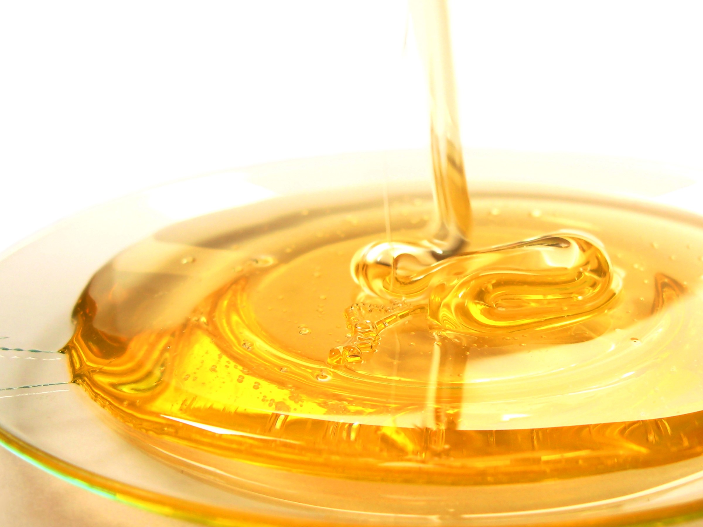 Honey pouring into a glass dish HD Wallpaper